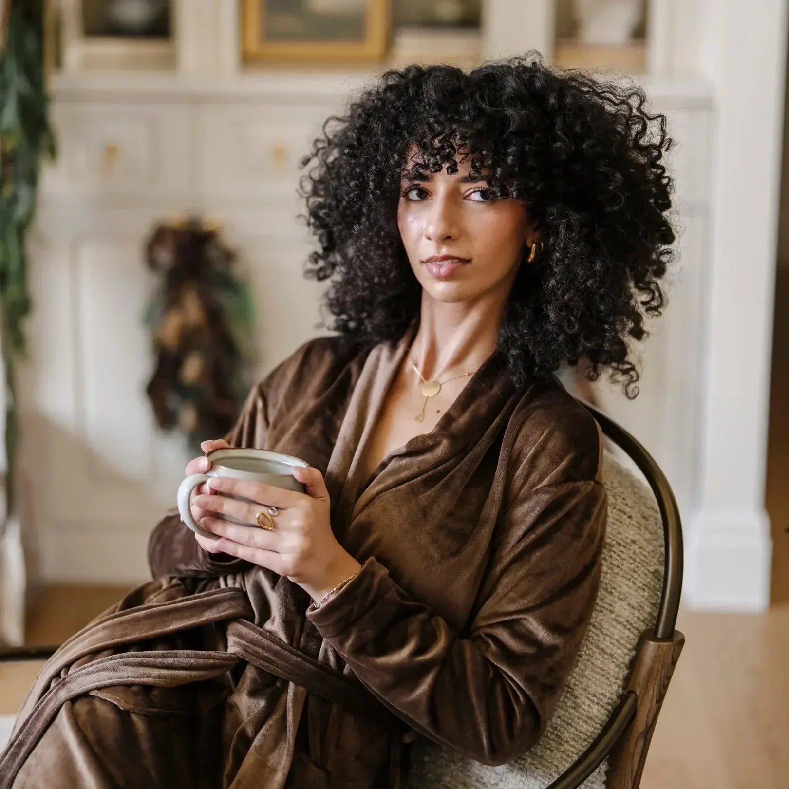 Woman in cozy brown robe holding mug, farmhouse living room decor