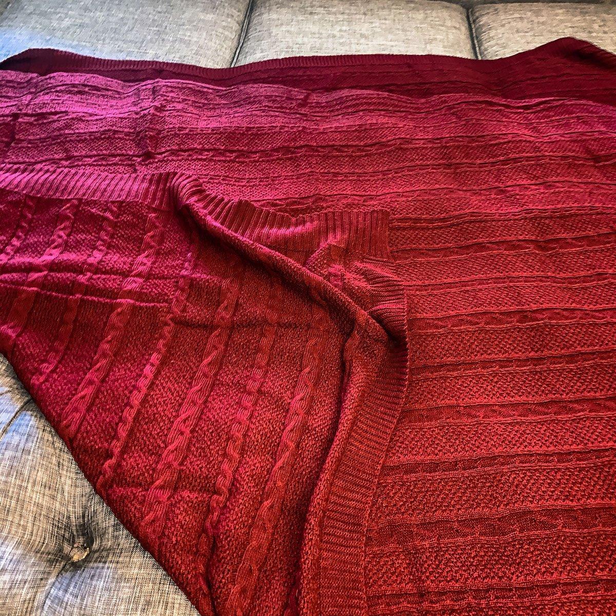 Cozy red cable knit blanket draped on farmhouse-style sofa for warm, inviting home decor