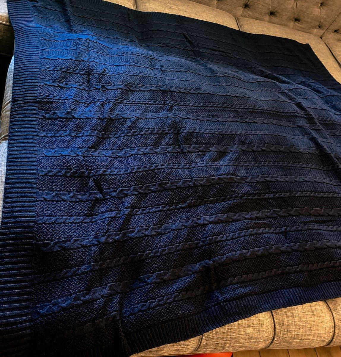Cozy navy blue cable knit throw blanket on tufted sofa, perfect for farmhouse or cottage decor