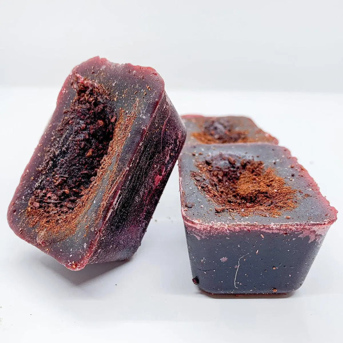 Two blocks of dark chocolate with a cocoa powder coating on a white background