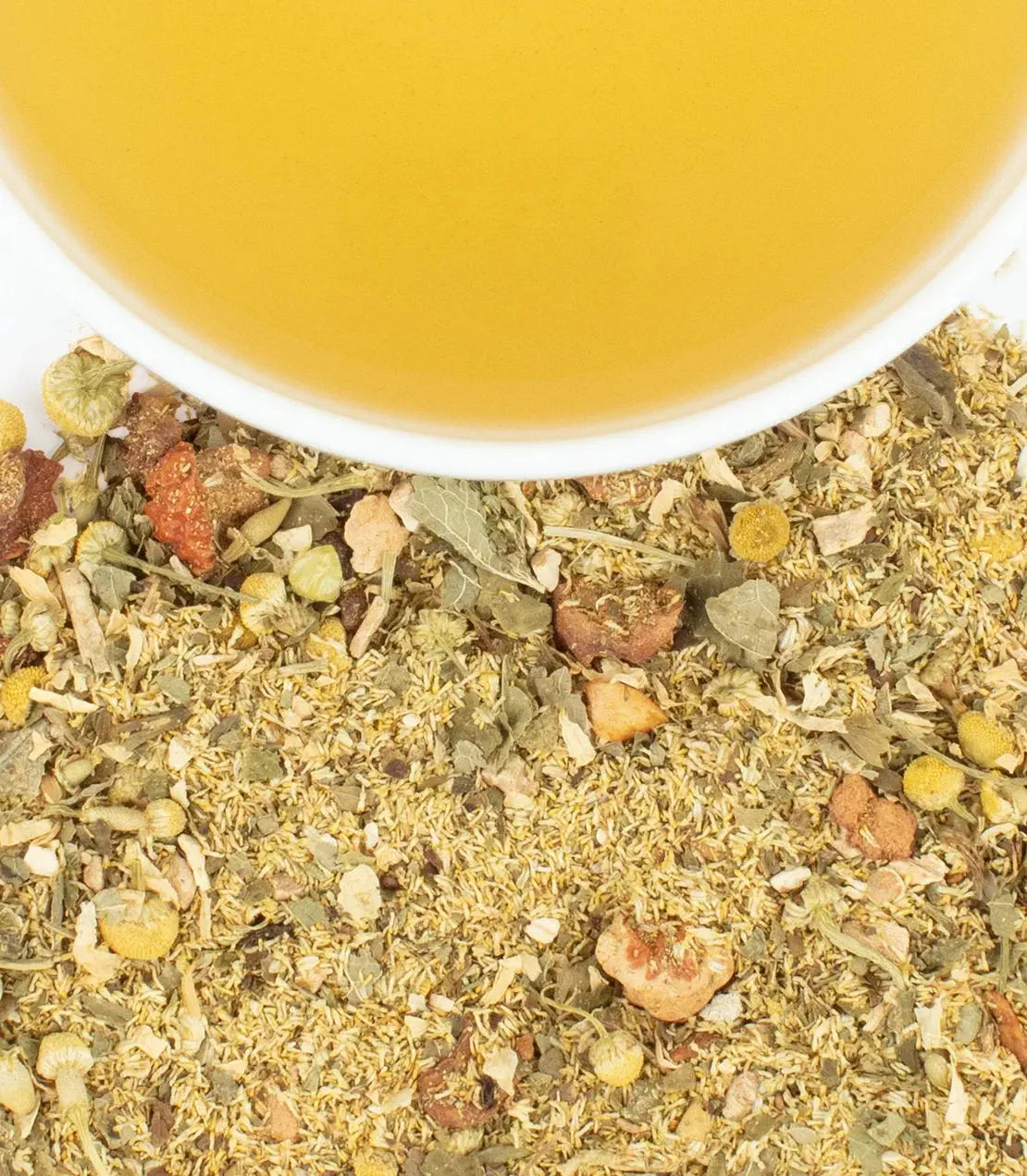 Herbal tea blend with chamomile and dried flowers beside a cup of golden tea, cozy home decor