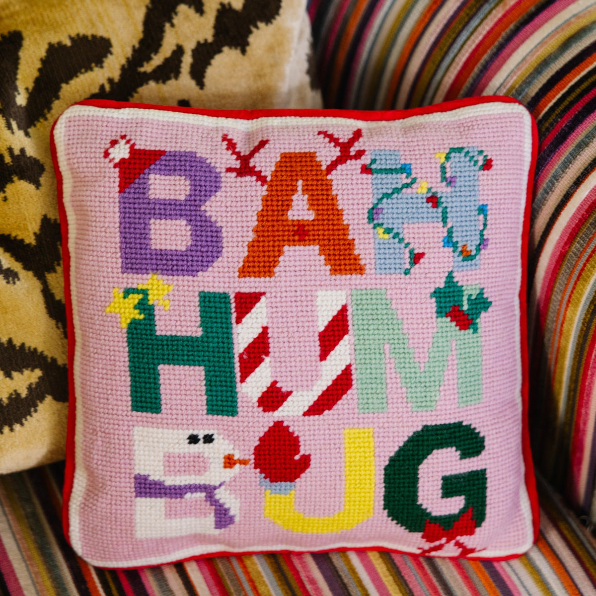 Decorative pillow with colorful letters on a striped couch