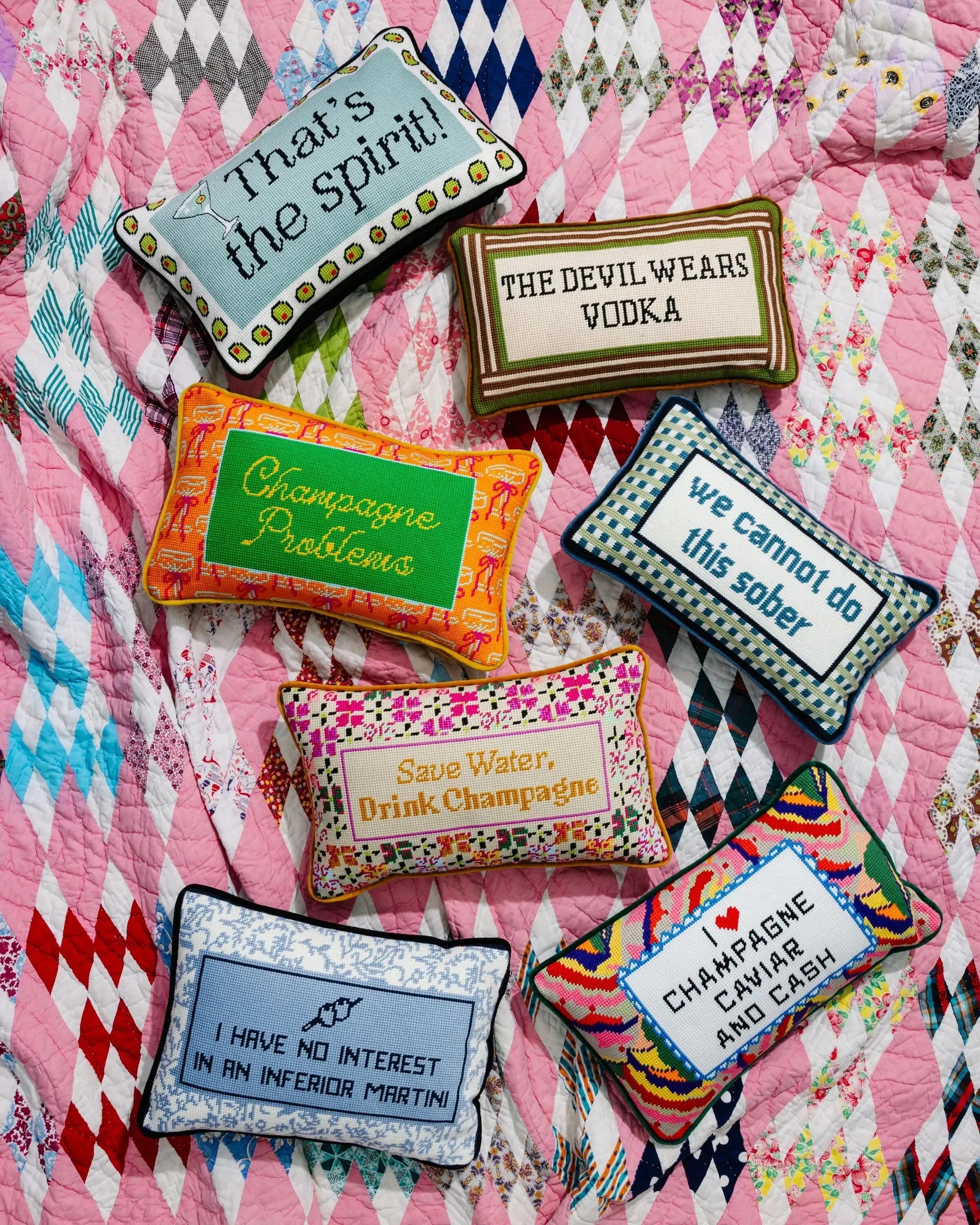 Colorful embroidered pillows with humorous sayings on a patterned fabric background