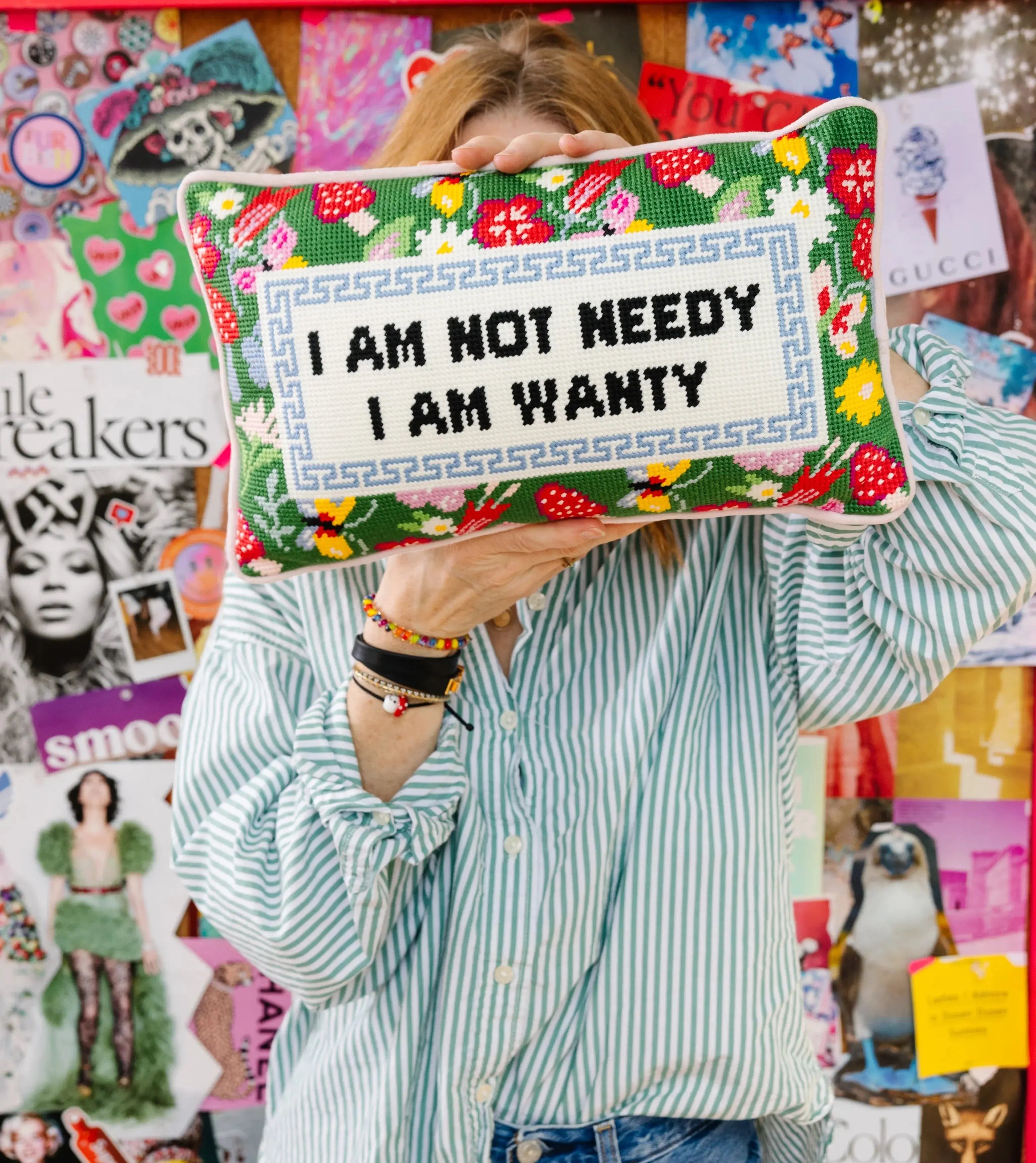A woman holding the Decorative pillow with floral patterns and text on it against a collage background