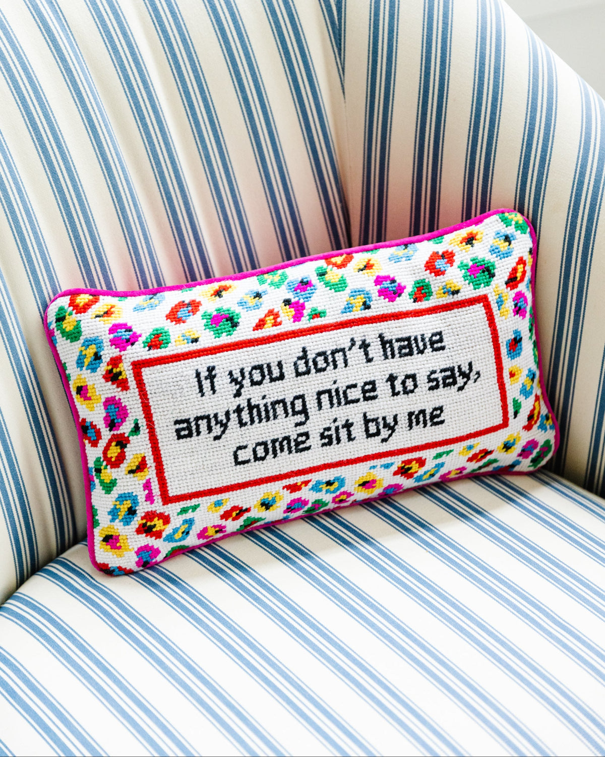 Decorative pillow with floral border and text on a striped chair