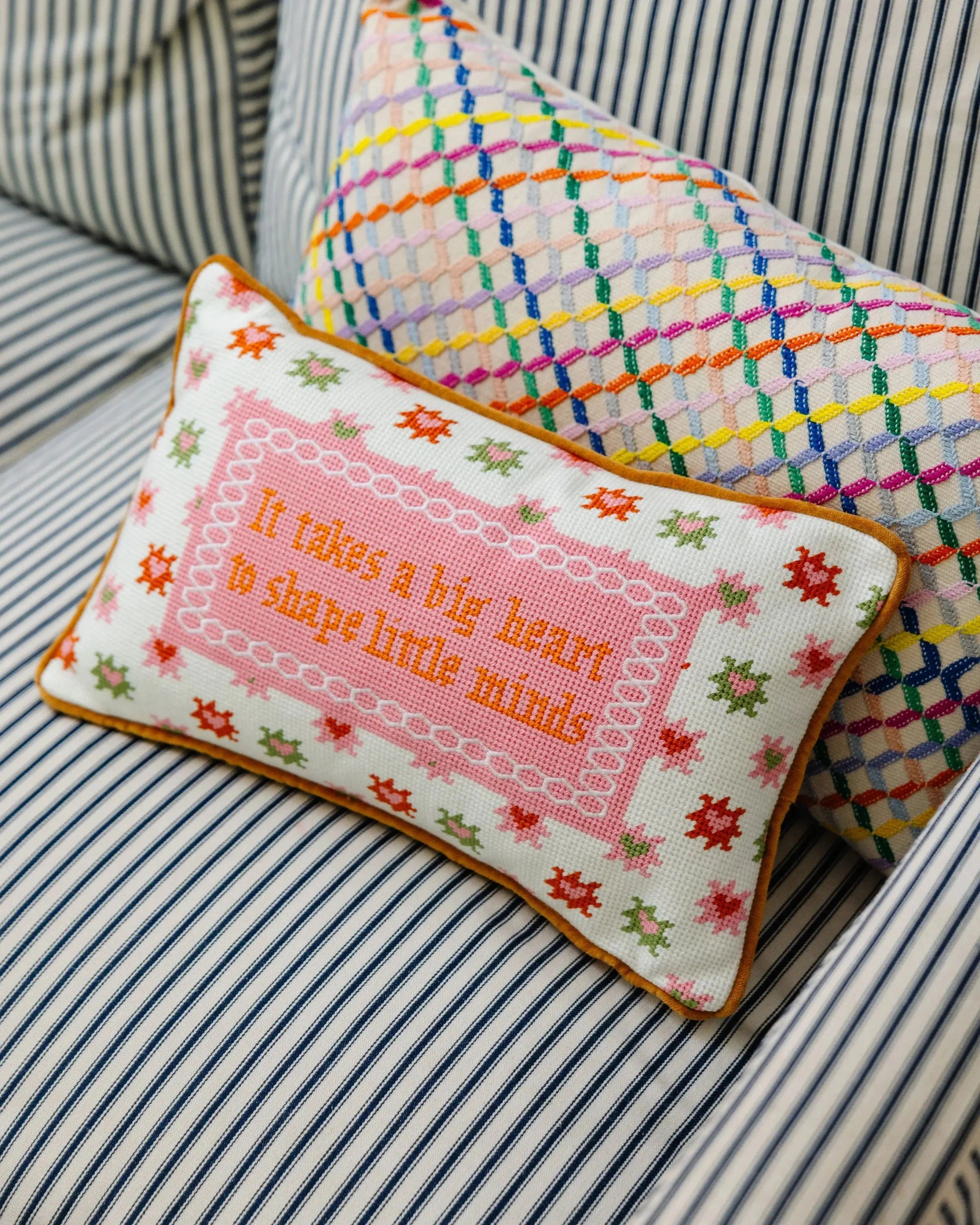 Decorative pillow with embroidered text on a striped fabric background