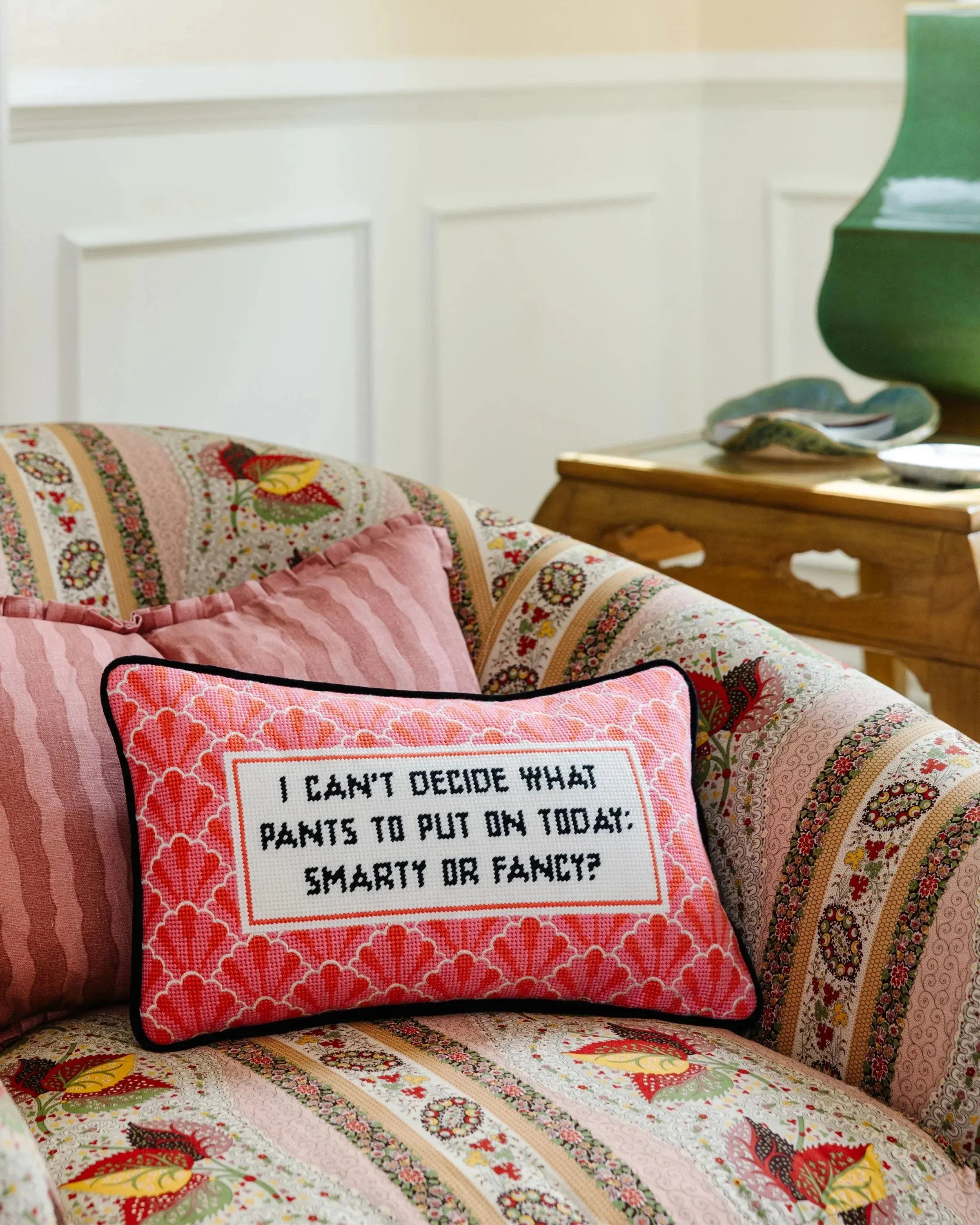 Decorative pillow with text on a patterned sofa in a home setting