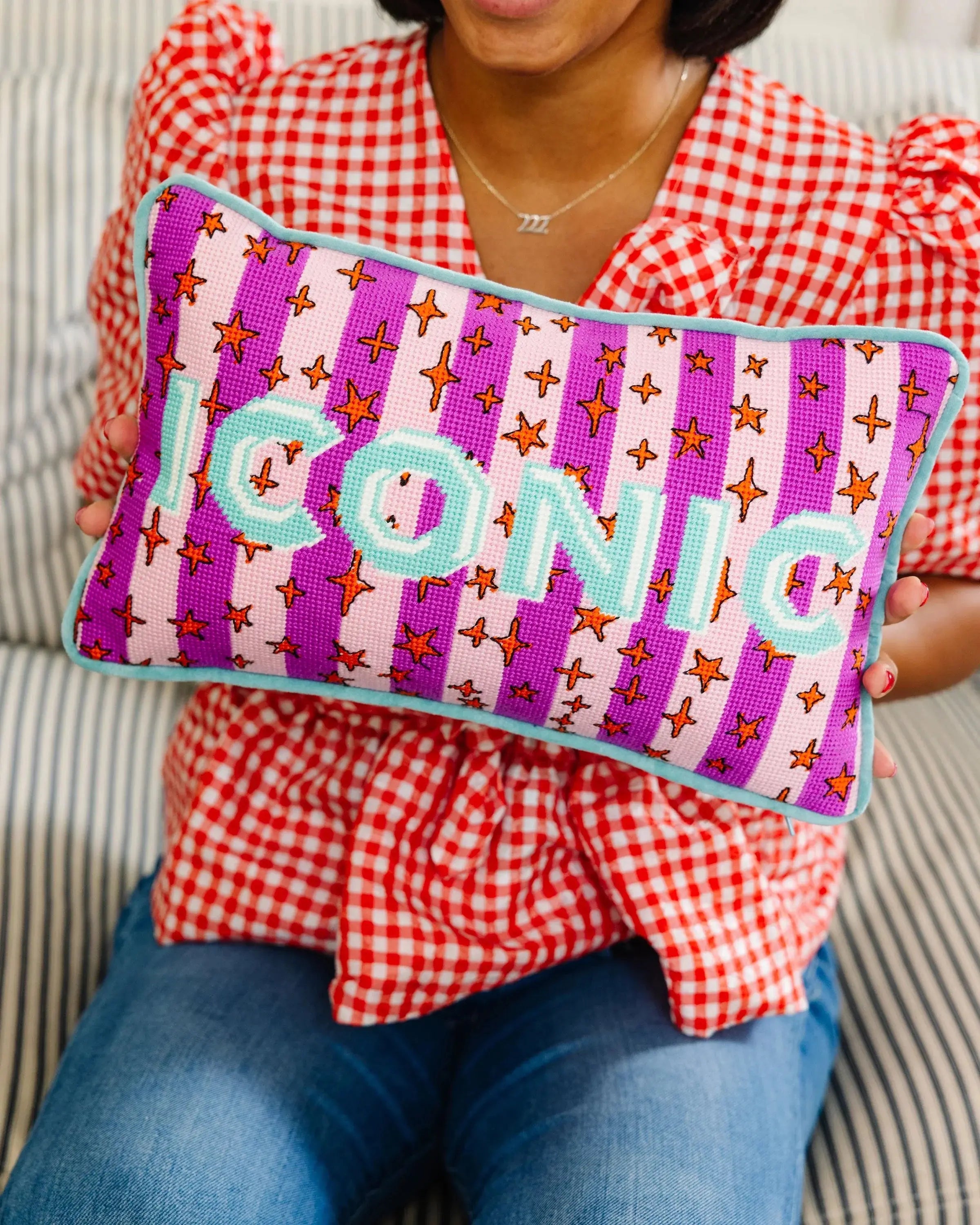 Person holding a colorful pillow with 'CONNIE' embroidered on it