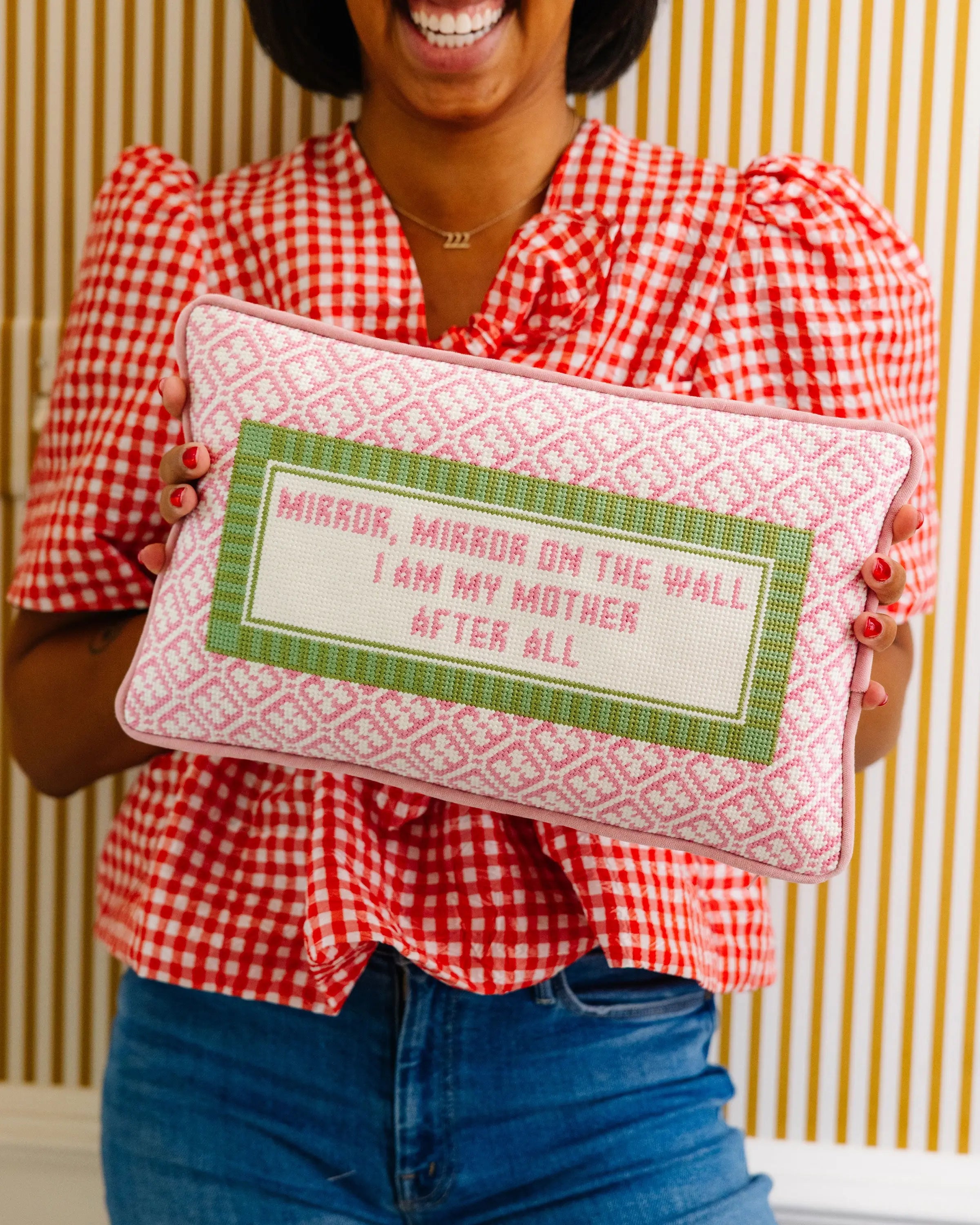 Woman in a red checkered shirt holding a decorative pillow with text