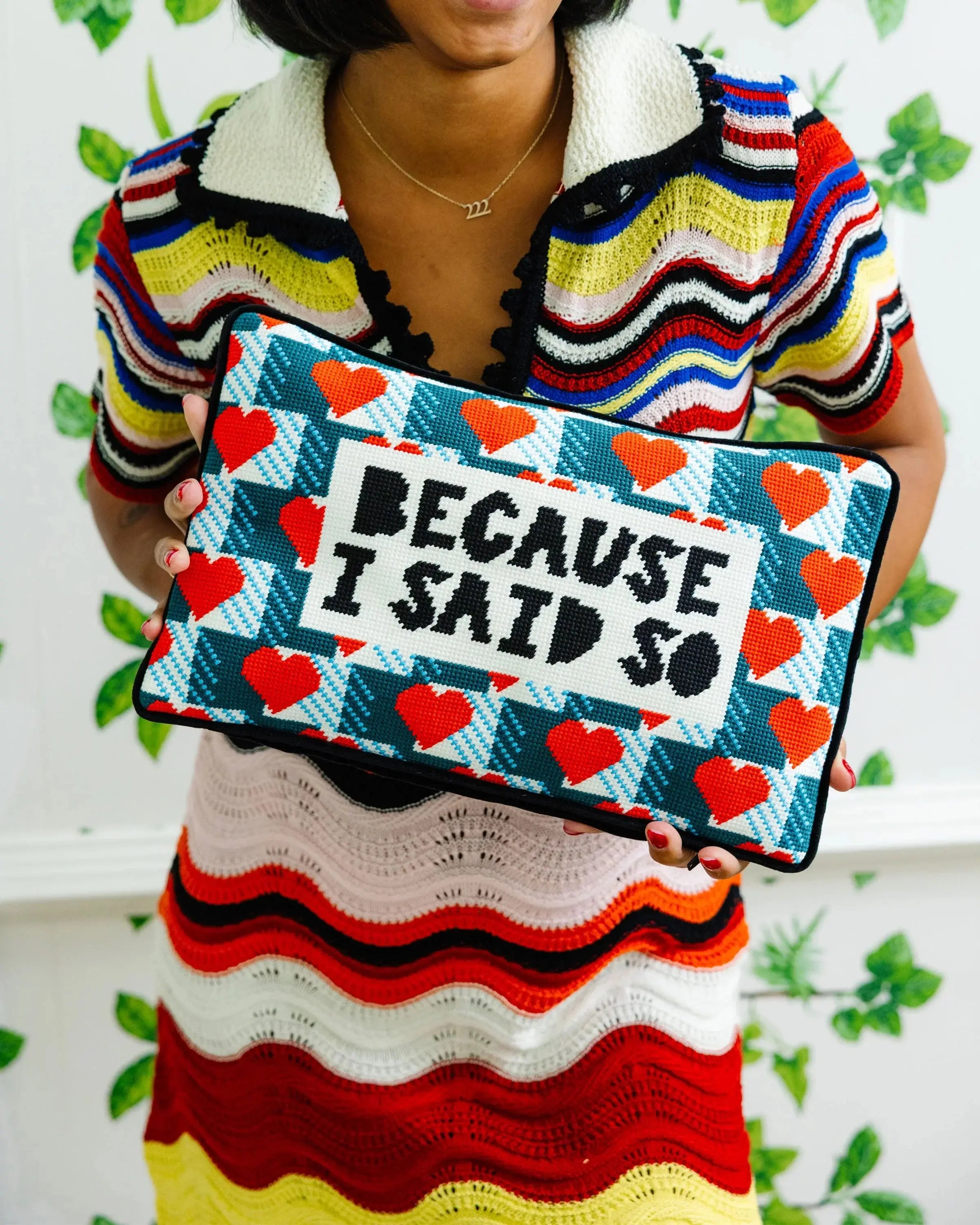 woman holding Decorative pillow with heart pattern and text 'Because I said so' against a decorative background