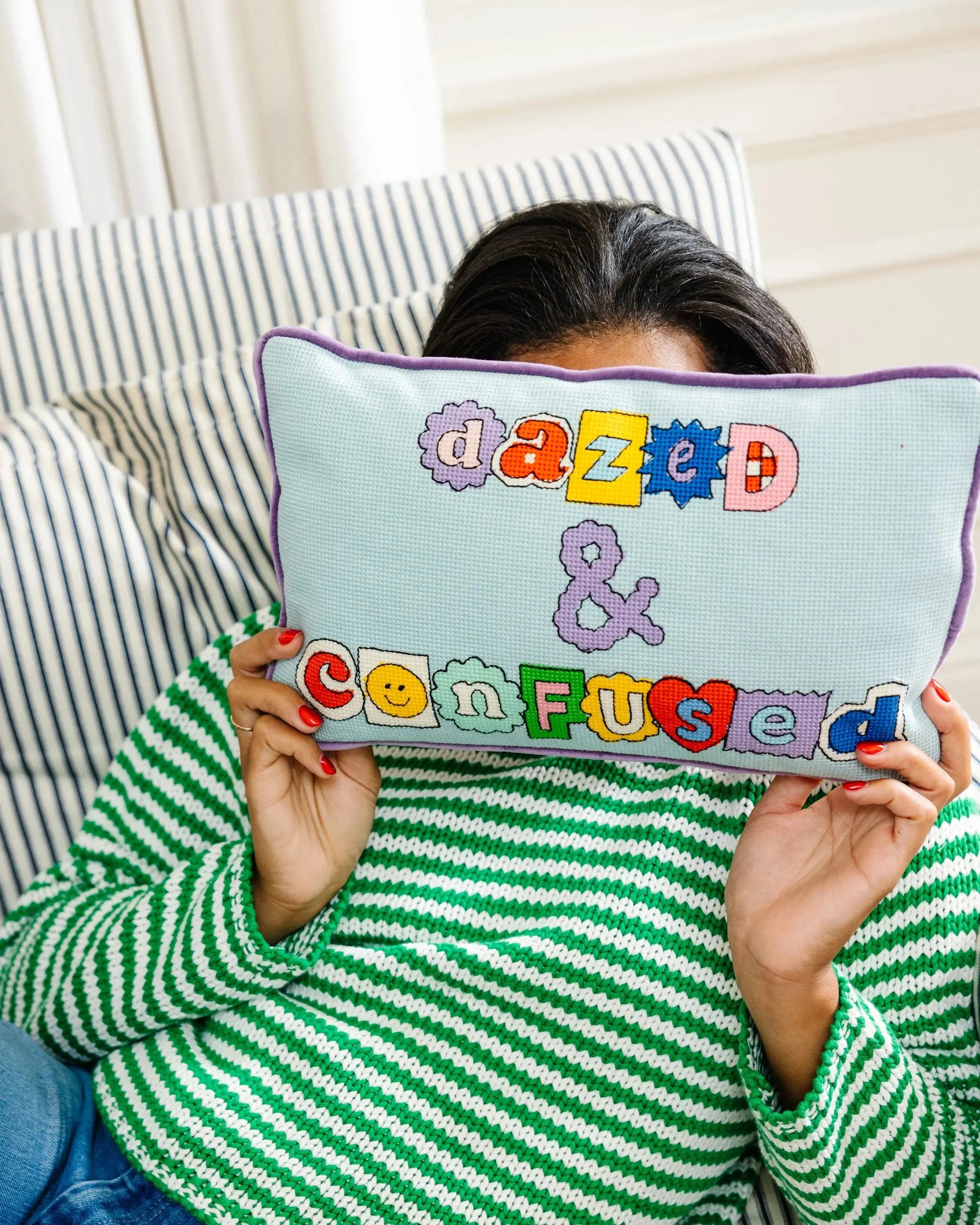 Person holding a pillow with 'dazed & confused' text in colorful letters.