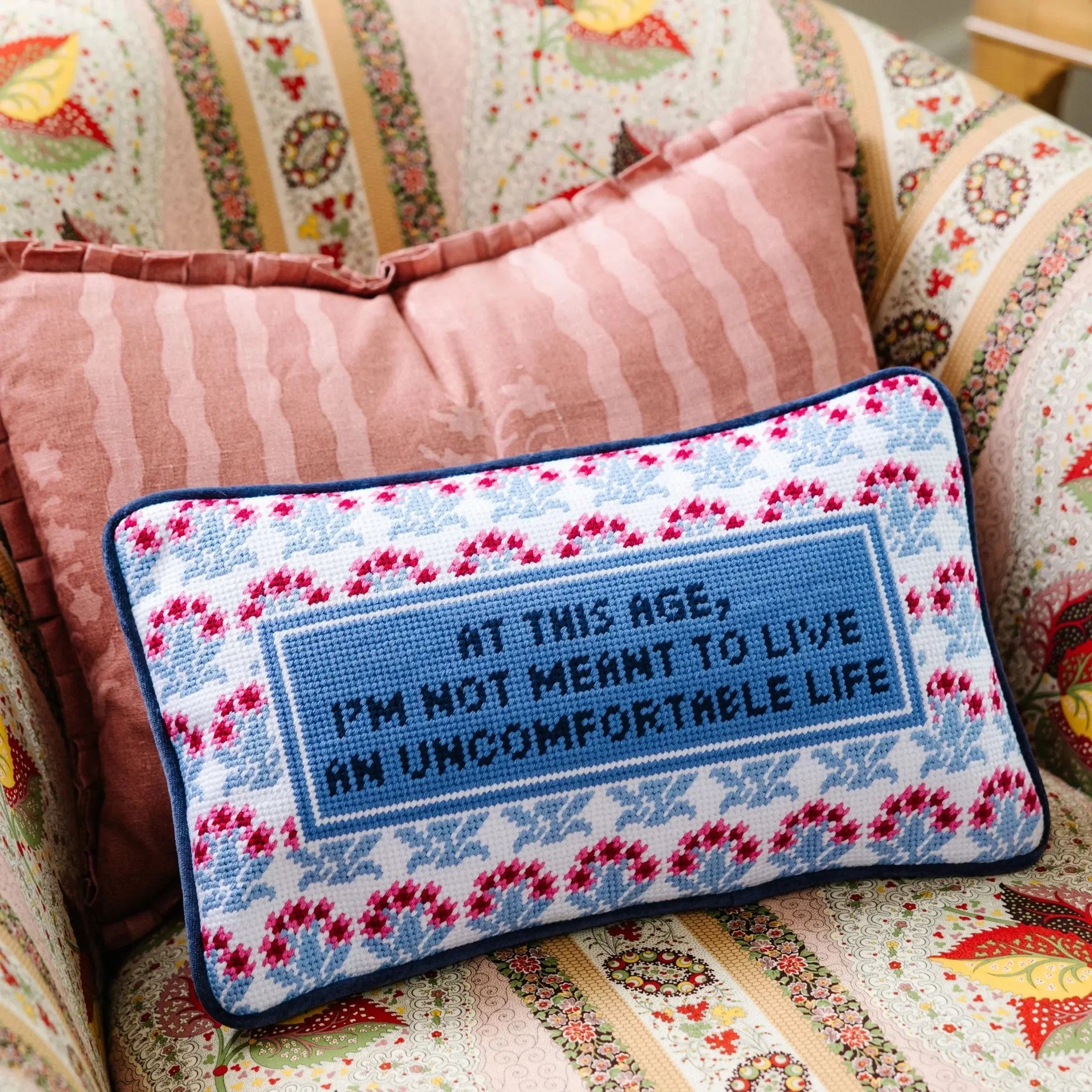 Cross-stitch pillow with 'At this age, I'm not meant to live an uncomfortable life' quote, farmhouse decor style