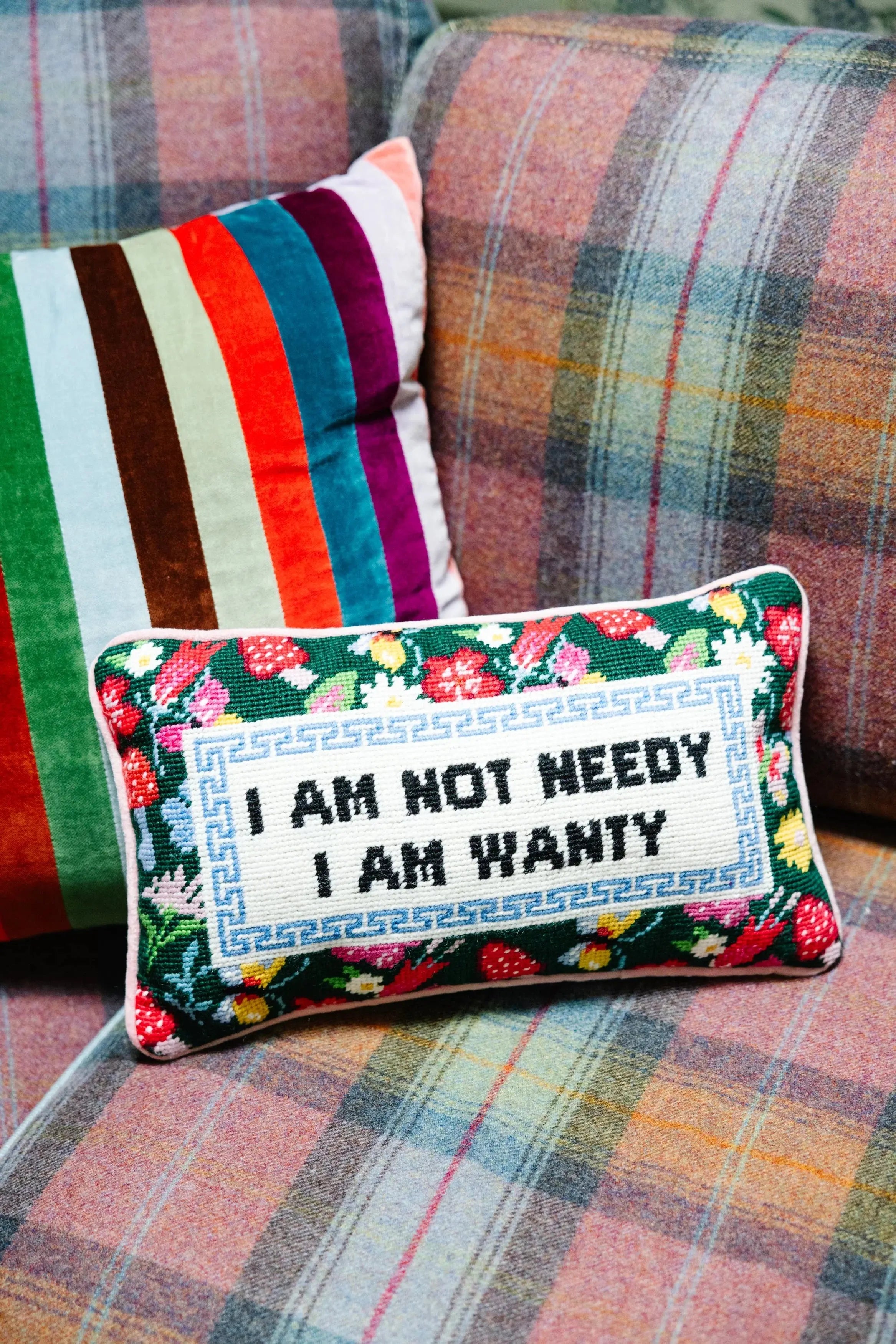 Decorative pillow with floral patterns and text on a plaid sofa