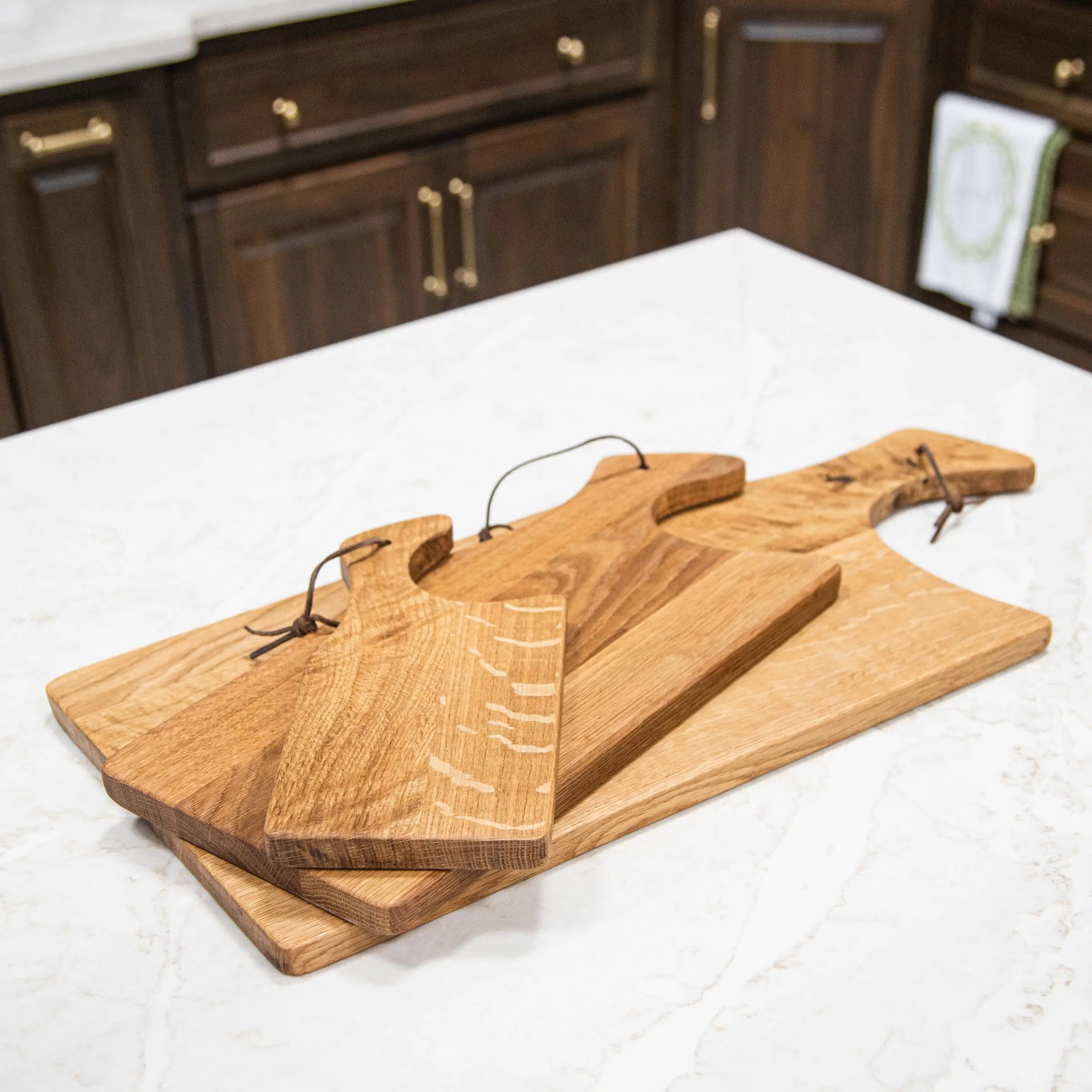 Set of wooden cutting boards on a kitchen counter with wooden cabinets in the background.