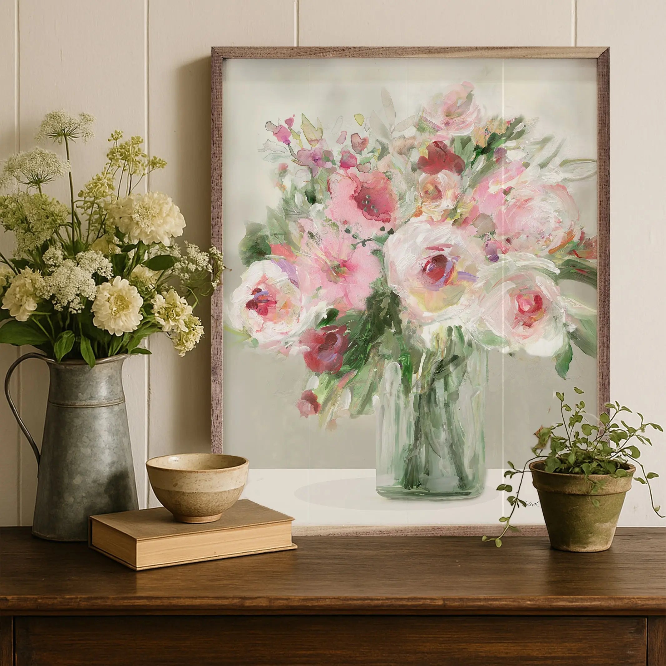 Framed floral artwork on a wooden surface with decorative items.