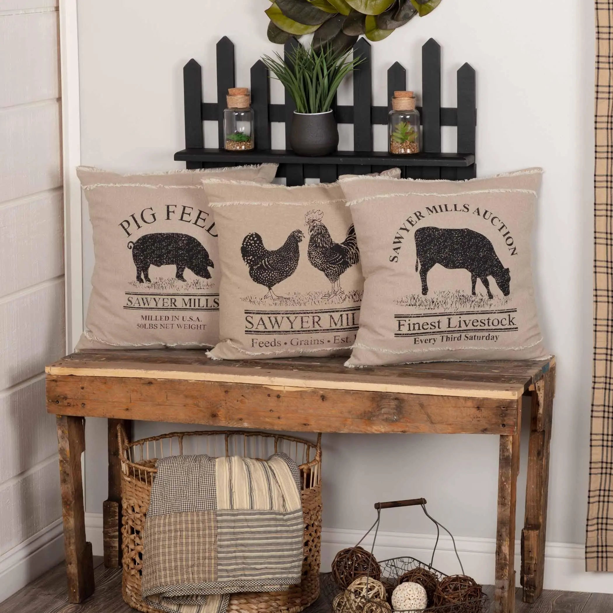 Wooden bench with decorative pillows featuring farm animal illustrations and text, against a white wall.