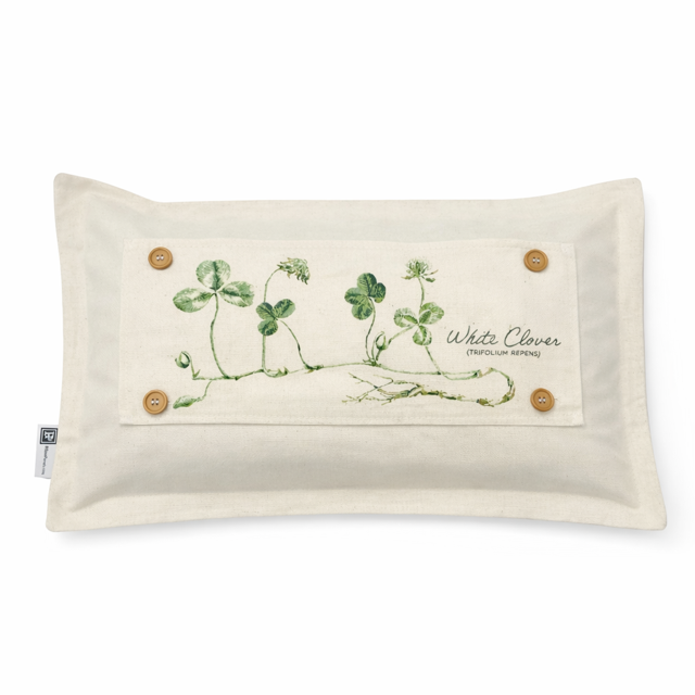 A rectangular cream-colored cushion featuring a central fabric patch with a green watercolor-style illustration of white clover and four wooden buttons, shown on a plain white background.