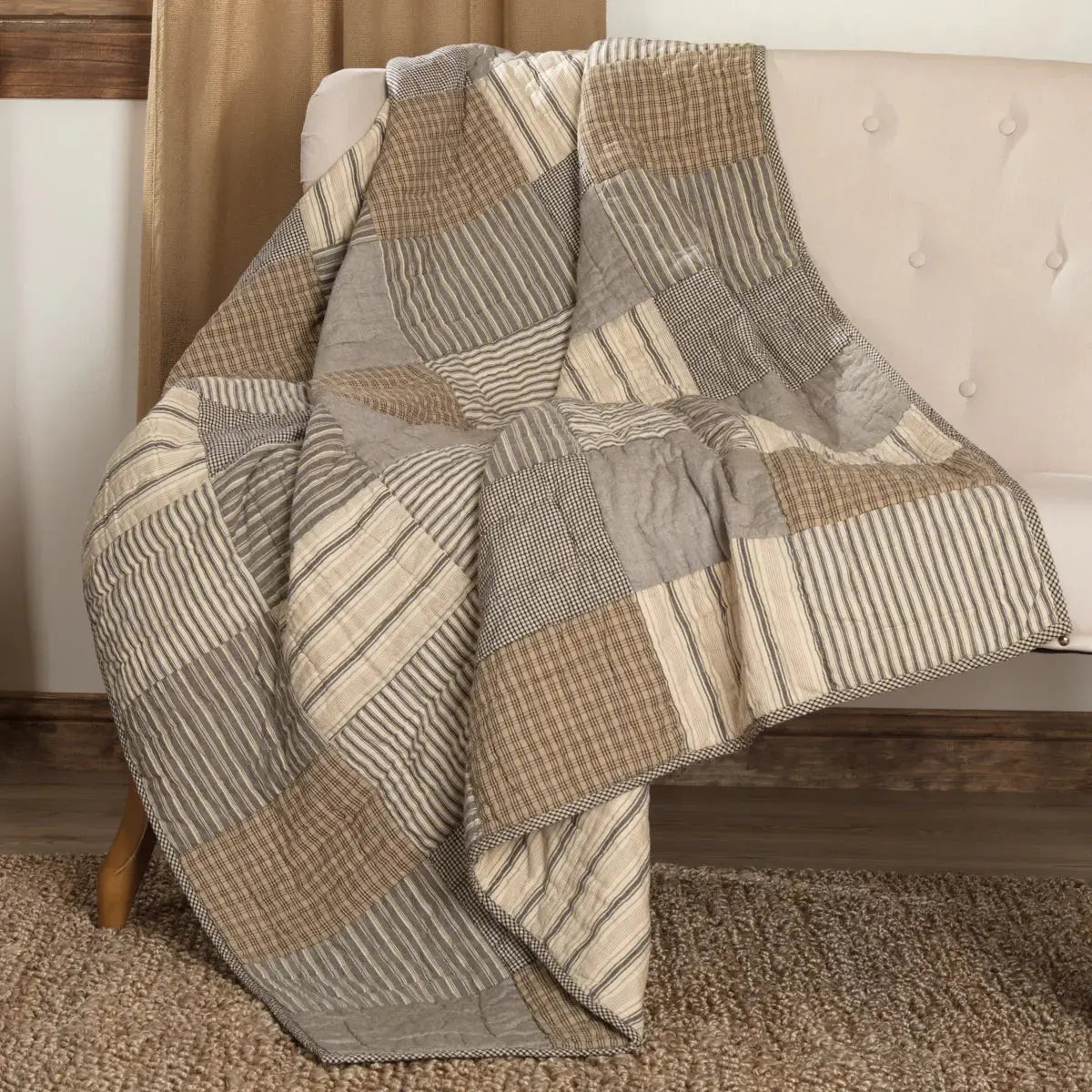 Cozy patchwork quilt with stripes and plaids draped over a tufted sofa, perfect for farmhouse or cottage decor