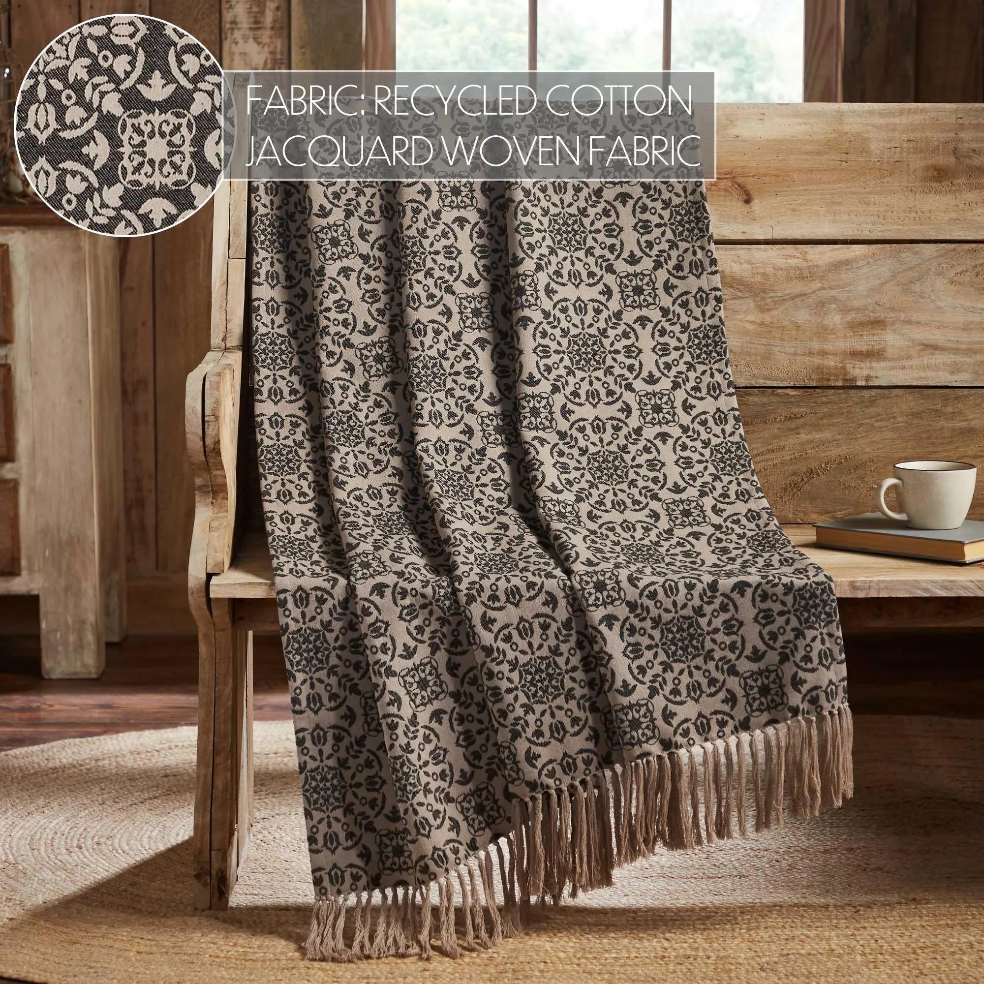 Cozy farmhouse throw blanket with black floral jacquard pattern and fringe, draped over wooden chair with candles