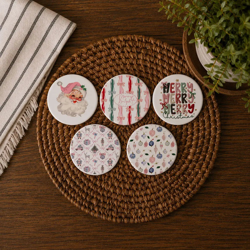 Set of five decorative coasters on a woven mat with a plant and towel in the background.