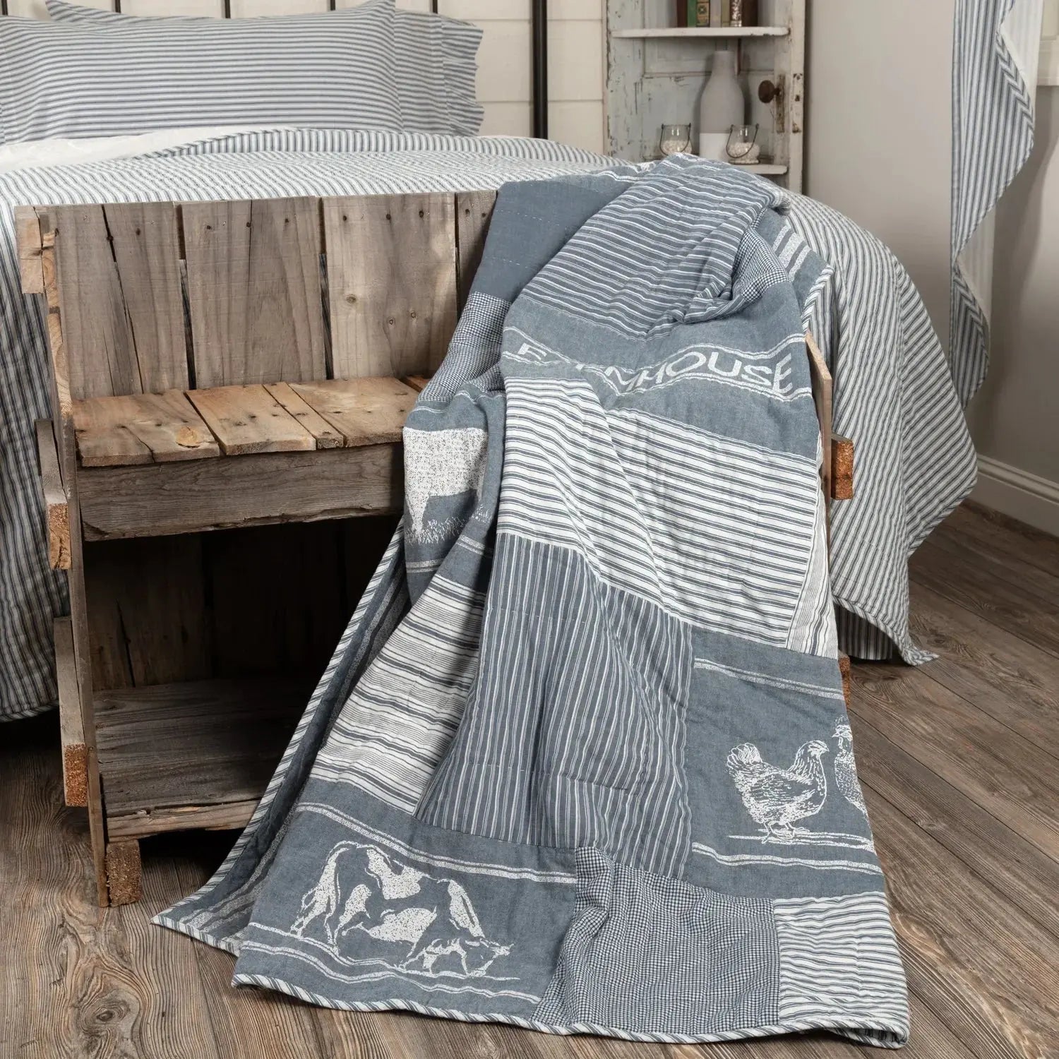 Blue and white patterned throw blanket draped over a wooden bench in a room with wooden flooring.