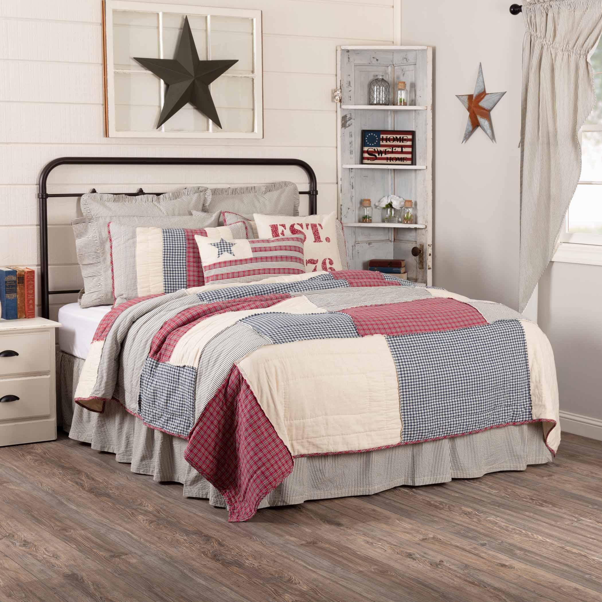 Red, white, and blue patchwork quilt set in farmhouse bedroom with star decor and rustic shelves