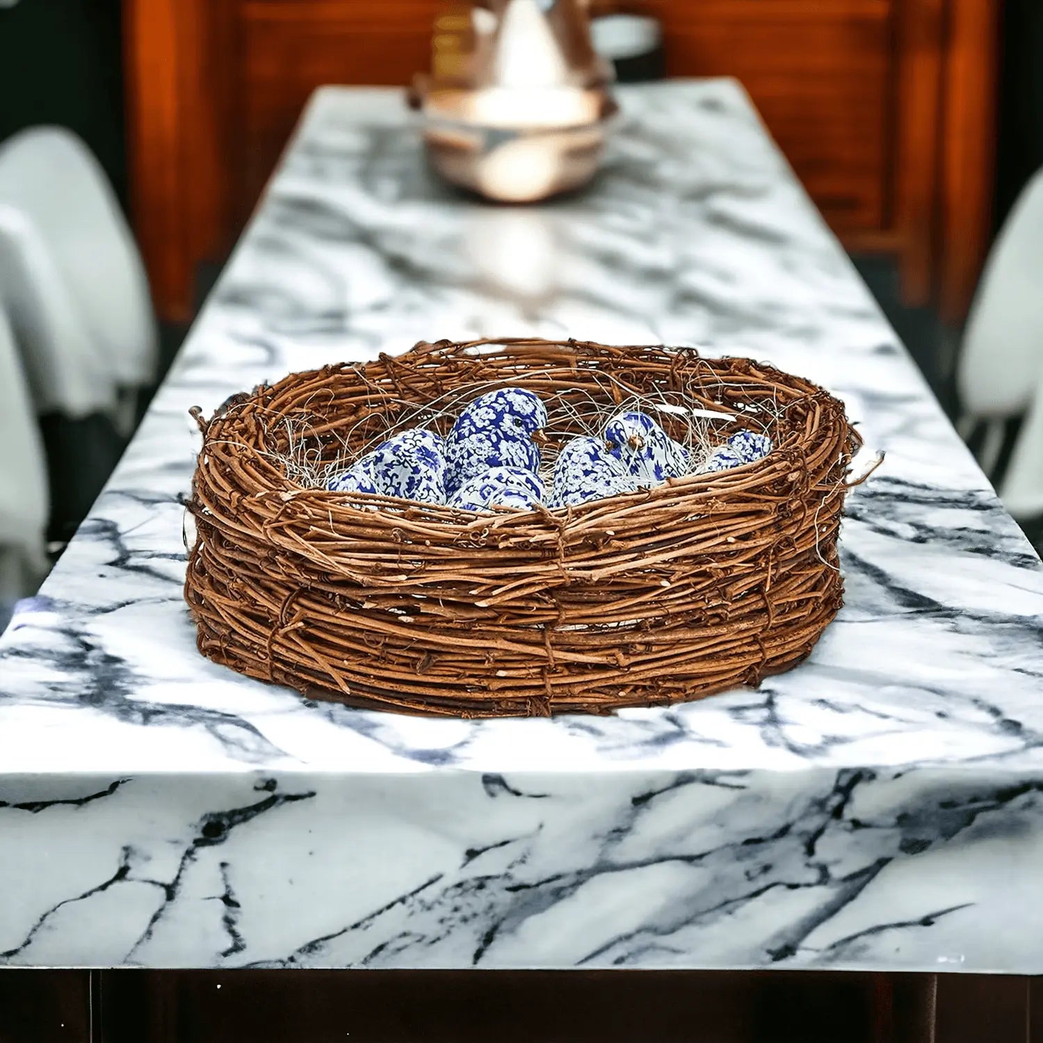 Decorative woven nest with blue and white ceramic pieces on a marble table.