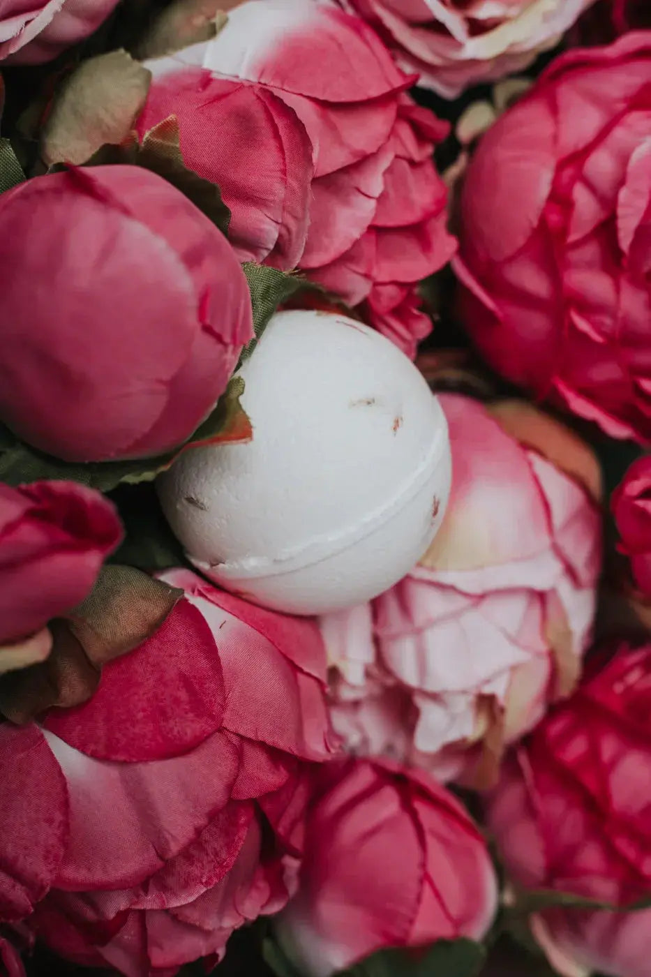 White bath bomb nestled among pink peony flowers, cozy farmhouse decor