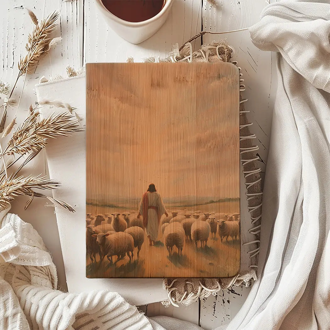 Wooden board with a pastoral scene of a shepherd and sheep, placed on a soft white surface with decorative elements.