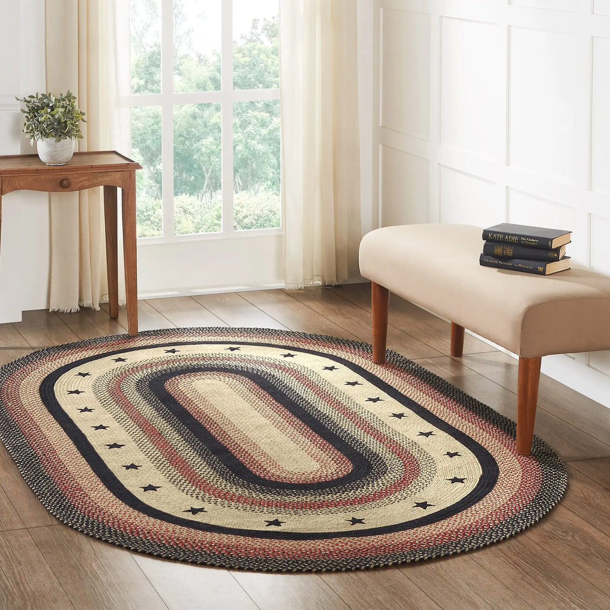 Oval braided rug on a wooden floor with a window and bench in the background