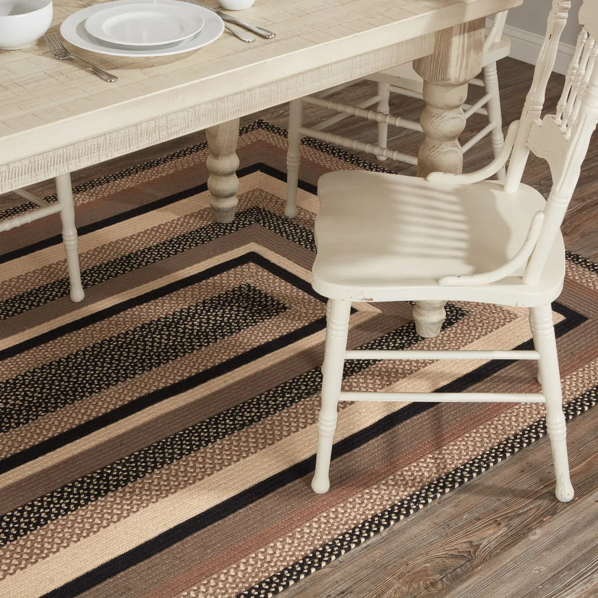 Dining table and chairs on a striped rug in a room with wooden flooring.