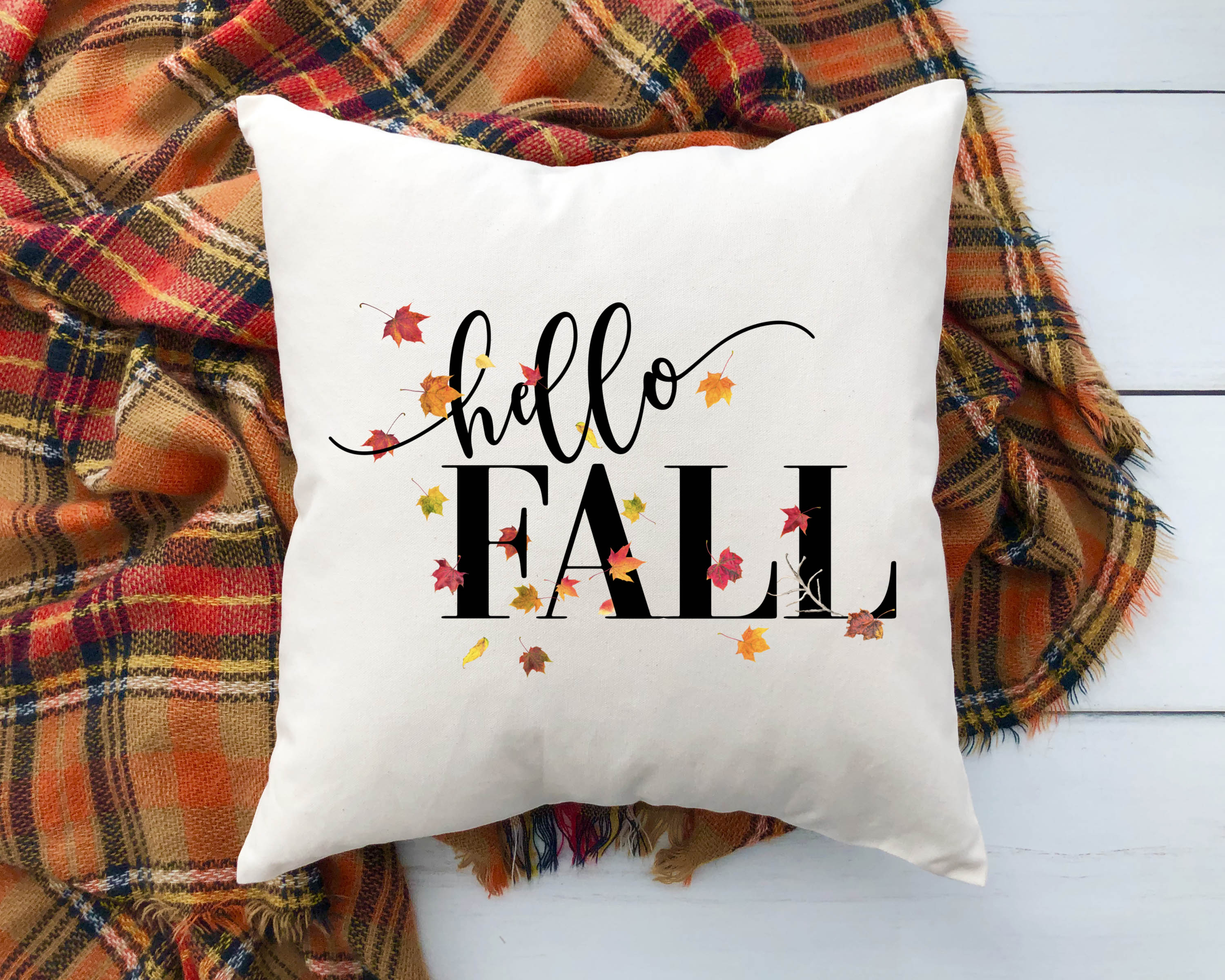 Decorative pillow with 'hello FALL' text on a plaid fabric background
