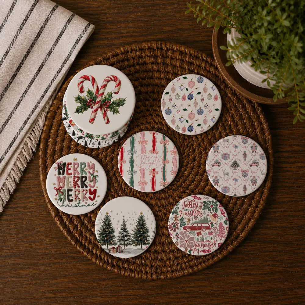 Set of Christmas-themed coasters on a woven mat with a plant and towel in the background.