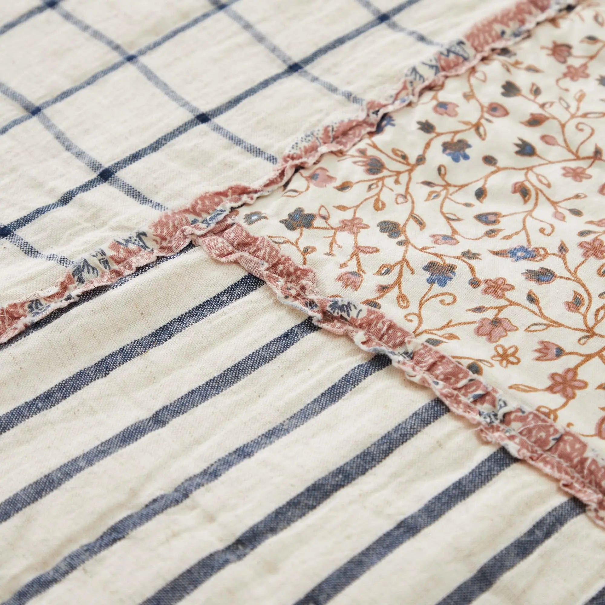 Cozy farmhouse quilt with blue stripes, floral patch, and ruffled trim for cottage-style home decor