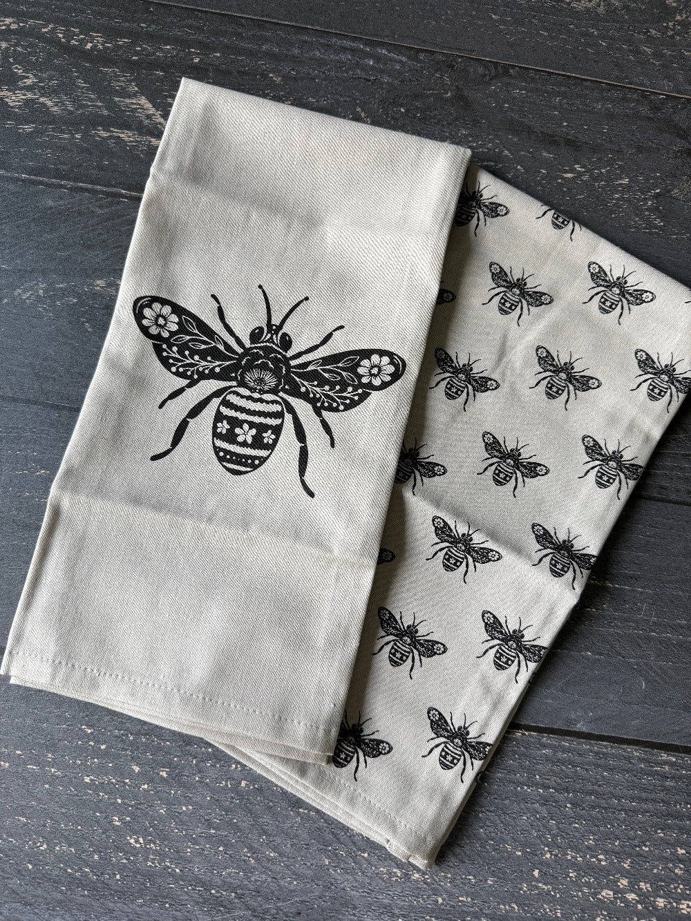 Two fabric towels with bee designs on a wooden surface