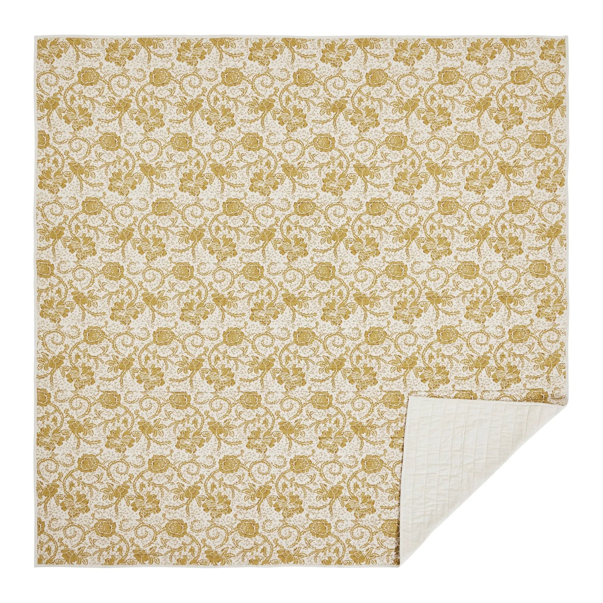 A square textile item, likely a blanket, quilt, or sheet, featuring an all-over damask-style floral pattern in a muted mustard yellow on a warm cream background. The bottom right corner is folded over to show the plain cream underside.