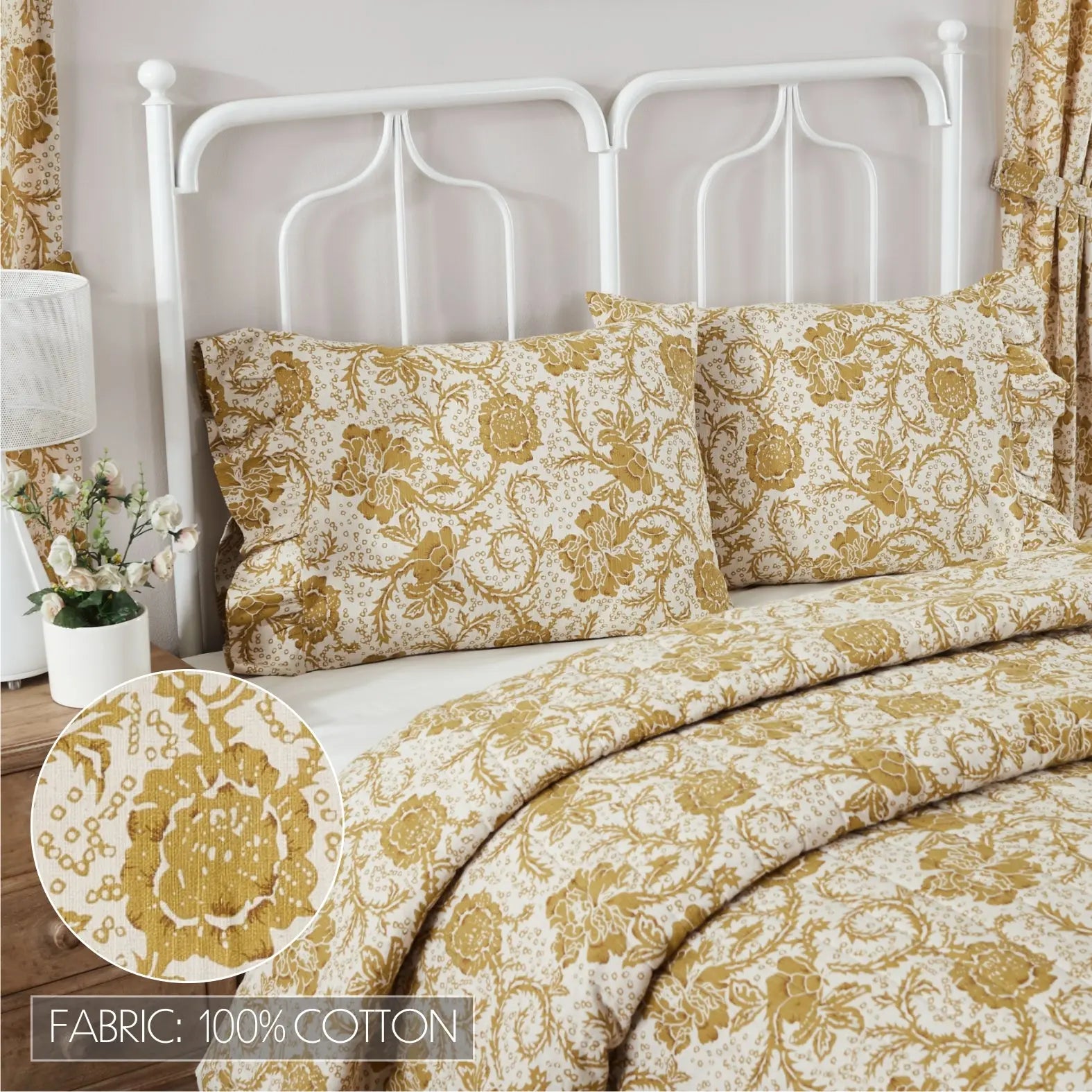 A bed dressed in a cream and mustard yellow damask-patterned cotton bedding set, with two matching pillowcases, a white metal headboard, and a fabric detail inset showing the 100% cotton material.