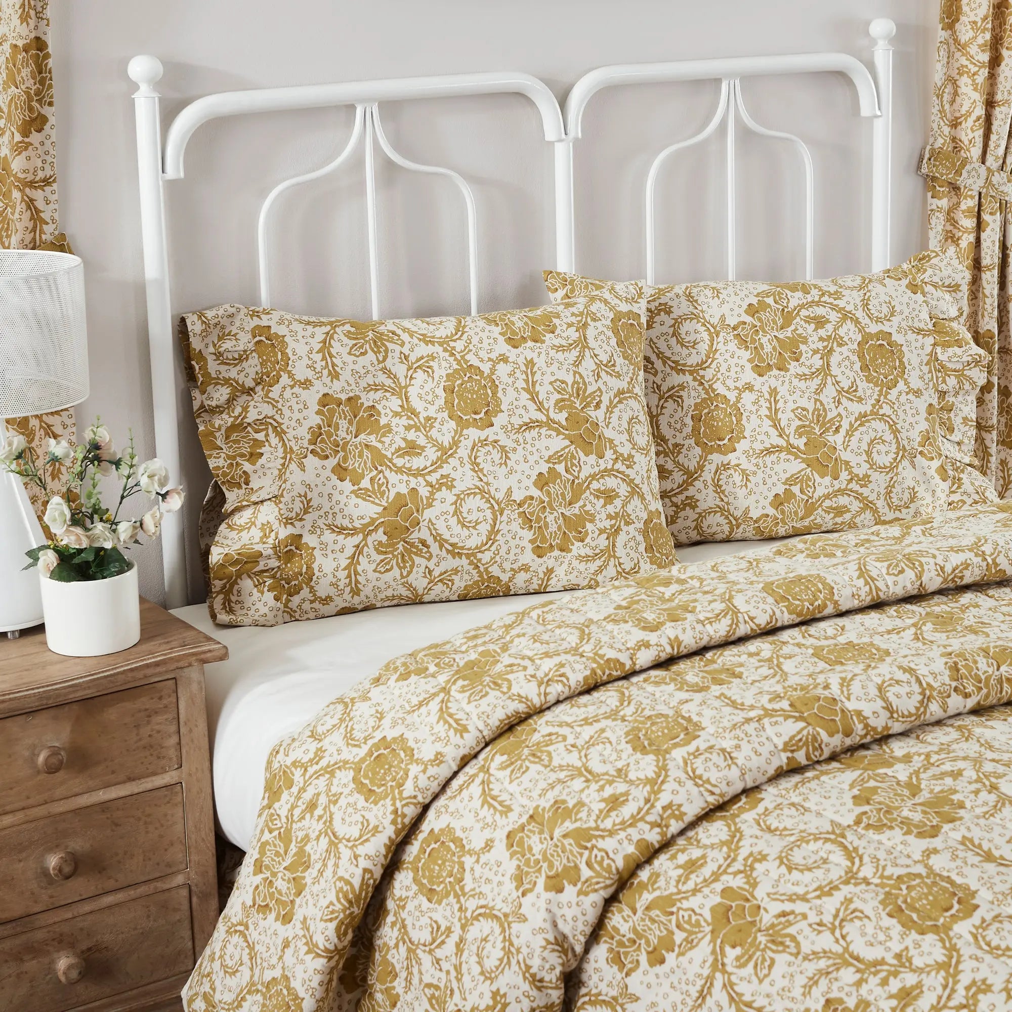 Bed with floral bedding and white headboard in a bedroom setting