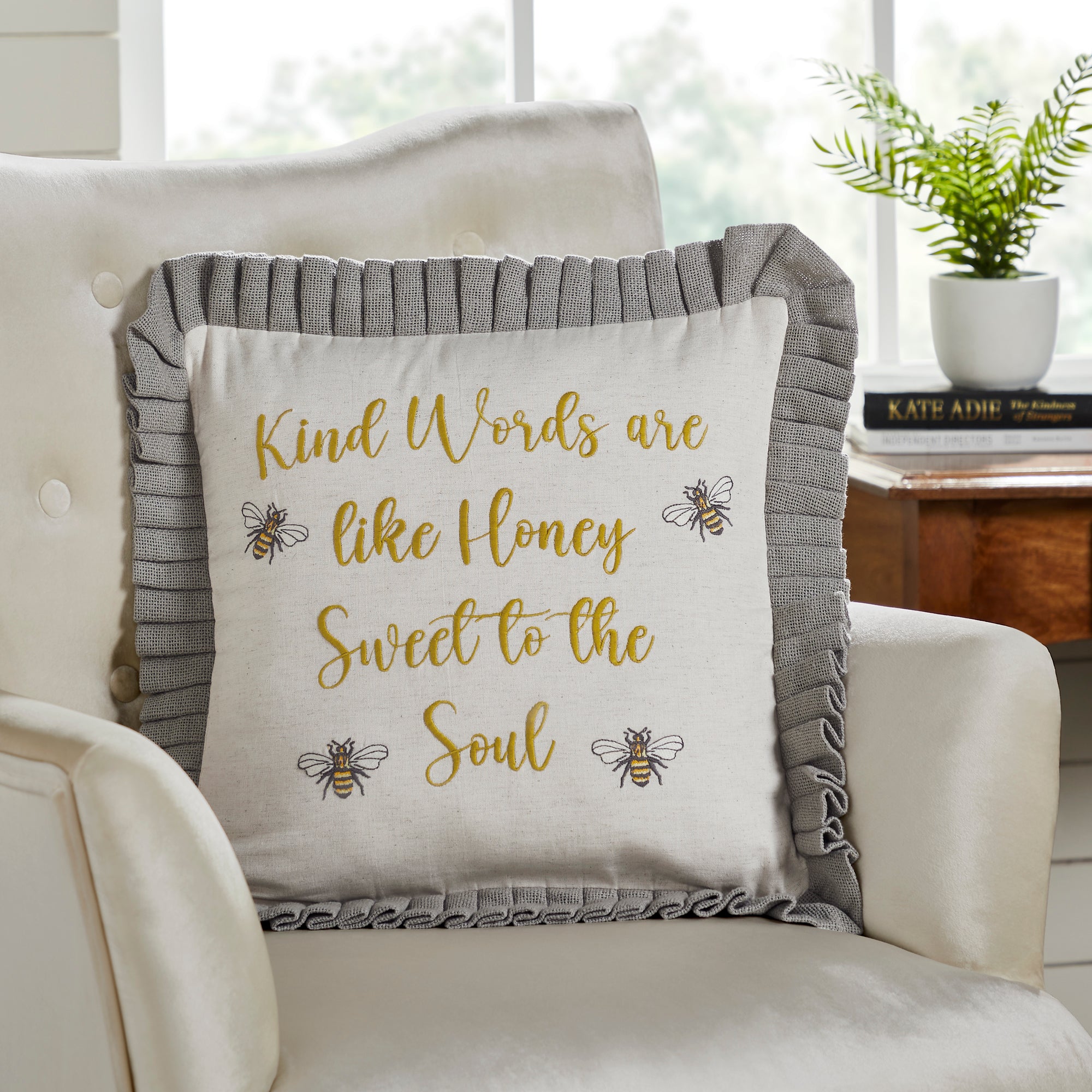 Decorative pillow with inspirational quote on a couch with a flower arrangement in the background