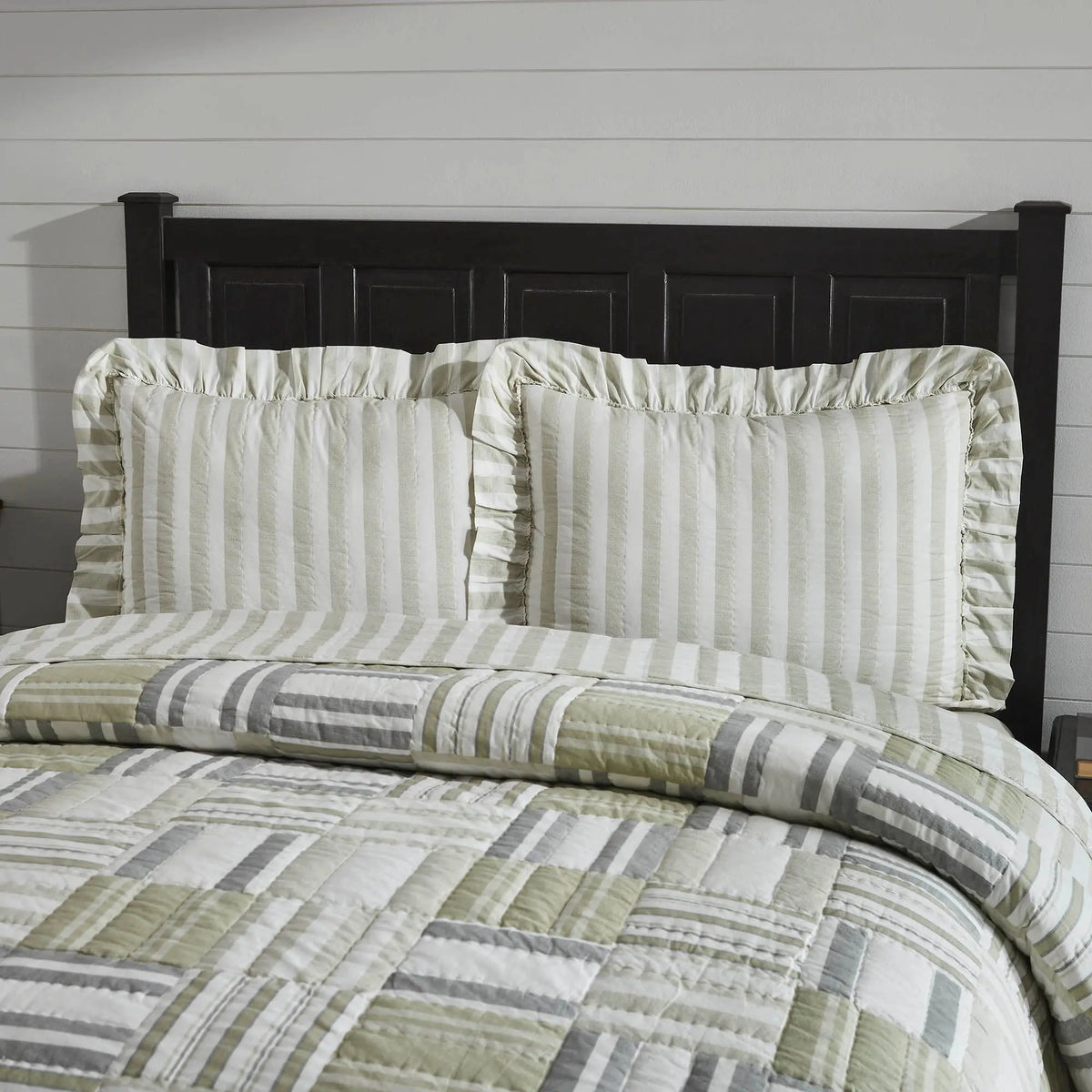 Bed with striped bedding and pillows against a wooden headboard.