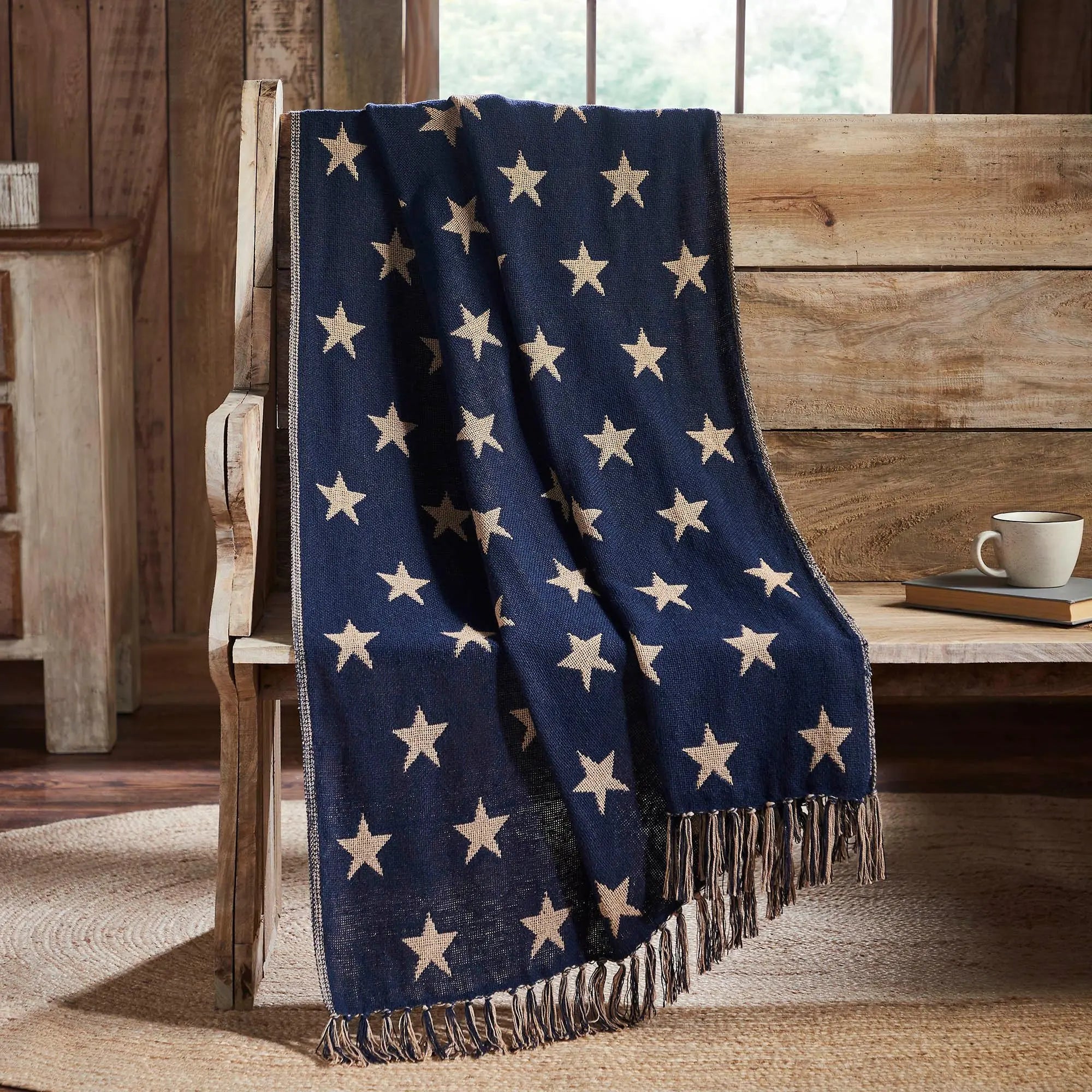 Navy blue blanket with beige stars draped over a wooden chair in a rustic setting.