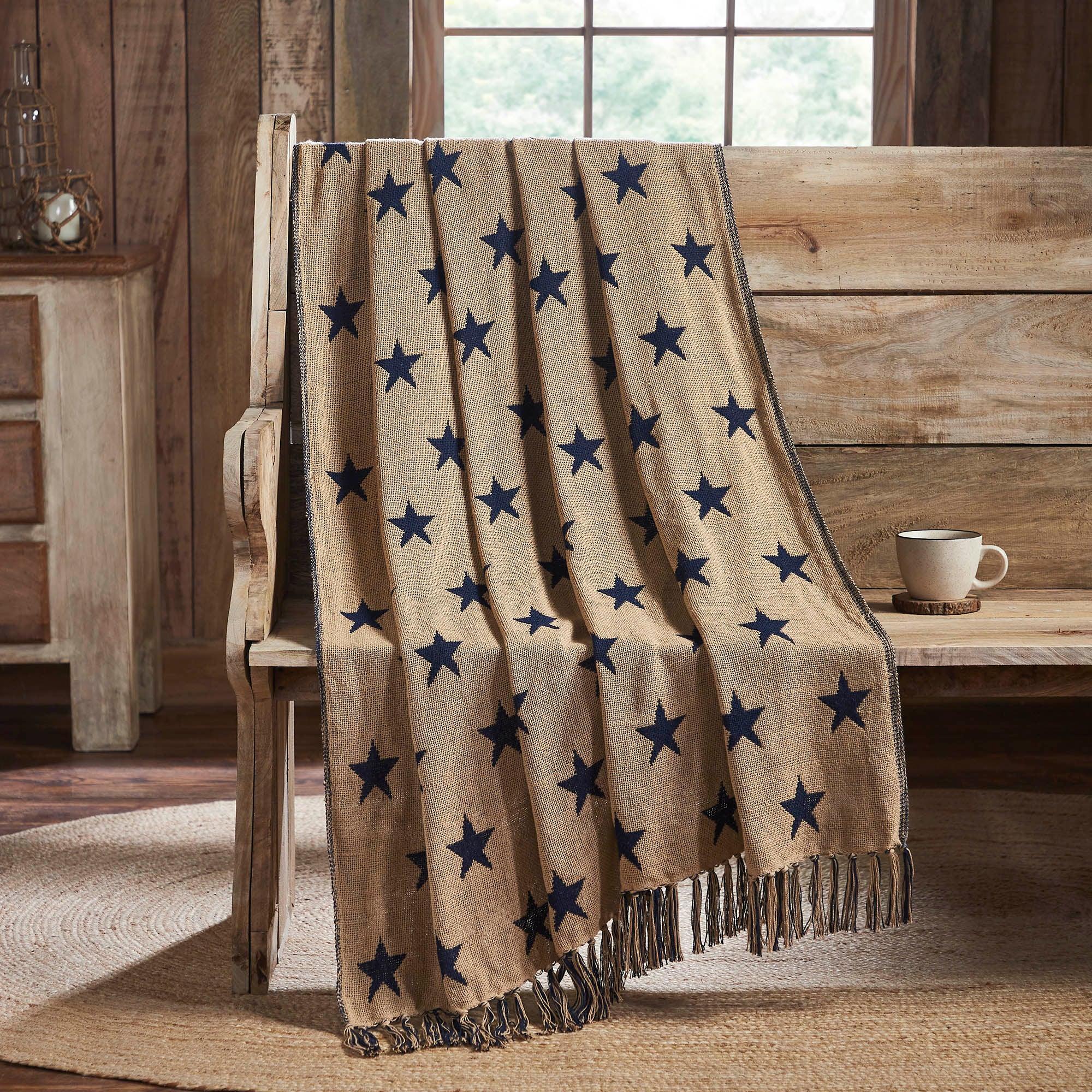 Beige blanket with blue stars draped over a wooden bench in a rustic setting.