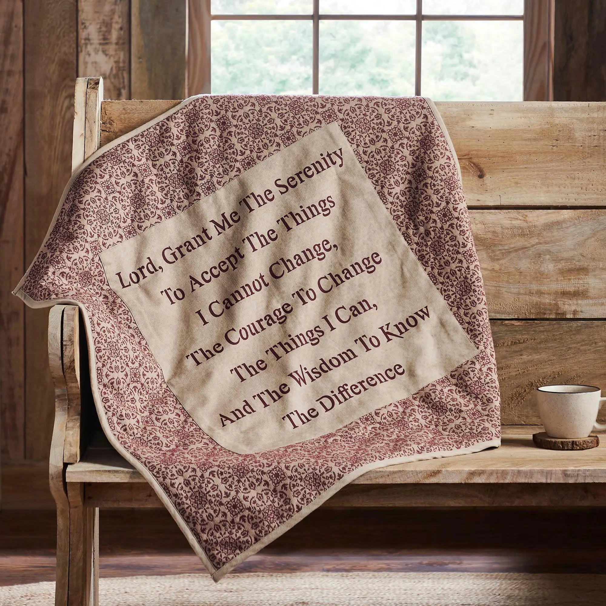 Serenity prayer blanket draped over a wooden bench in a rustic setting