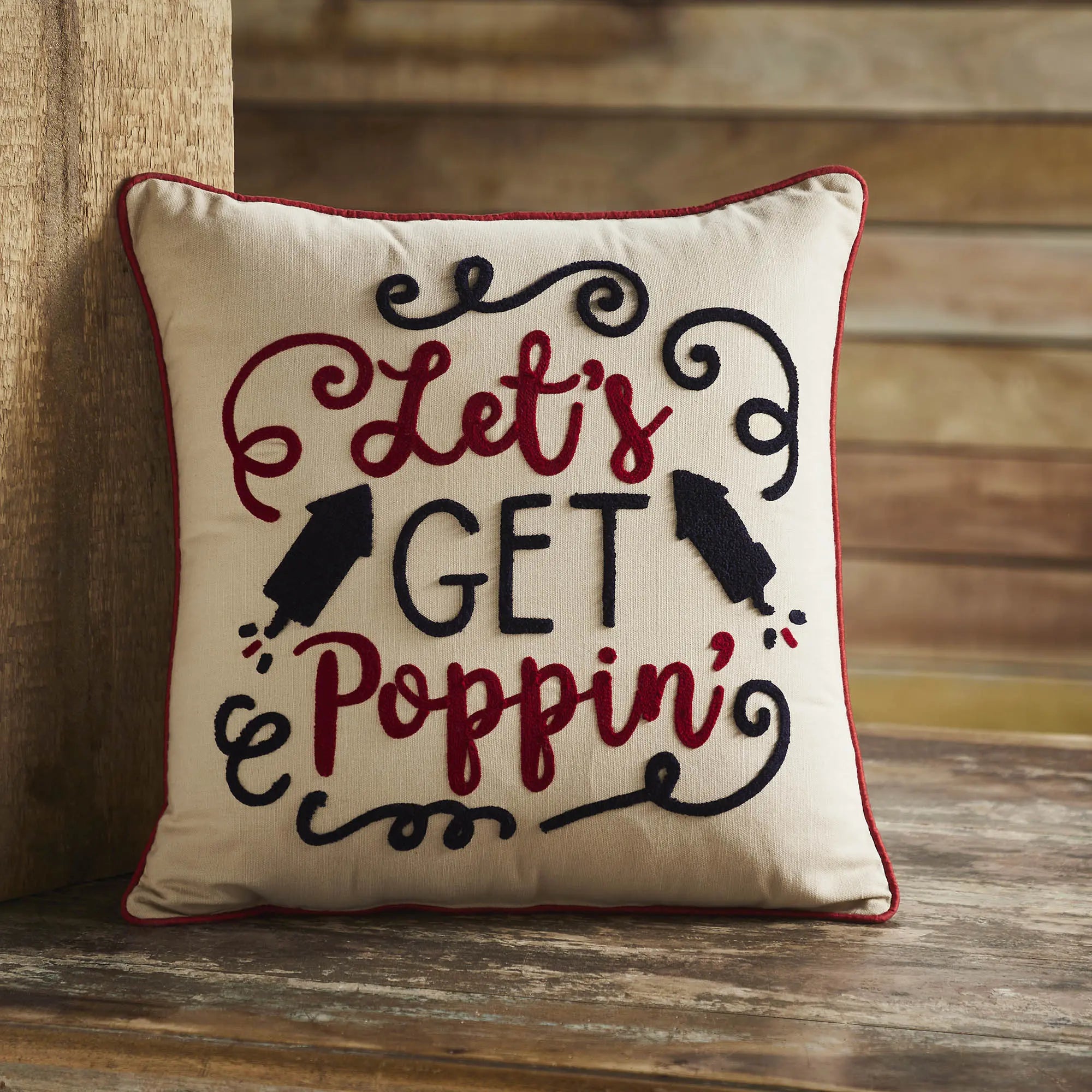 Decorative pillow with 'Let's Get Poppin'' text on a wooden surface