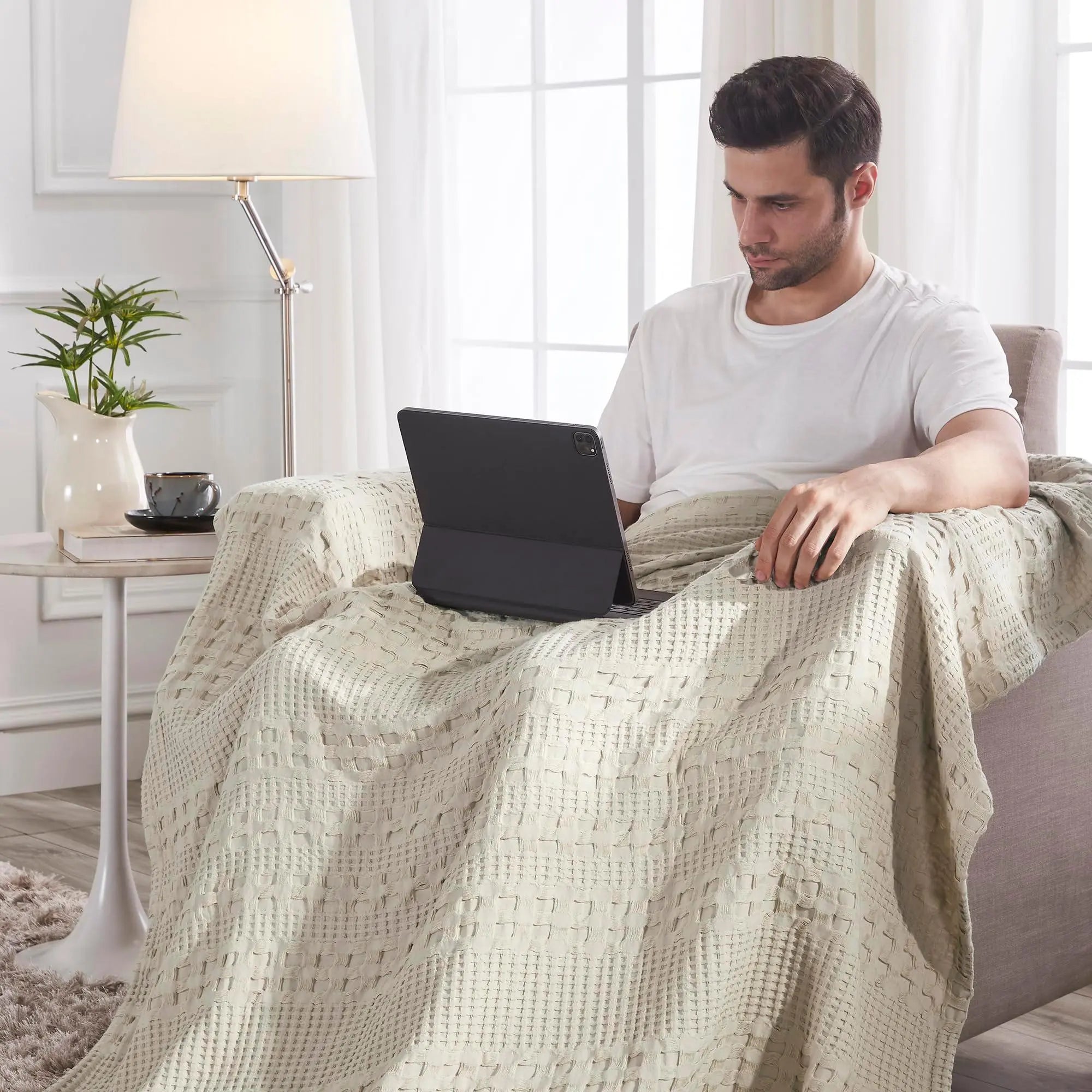 Cozy beige waffle knit throw blanket draped over man using tablet in farmhouse living room