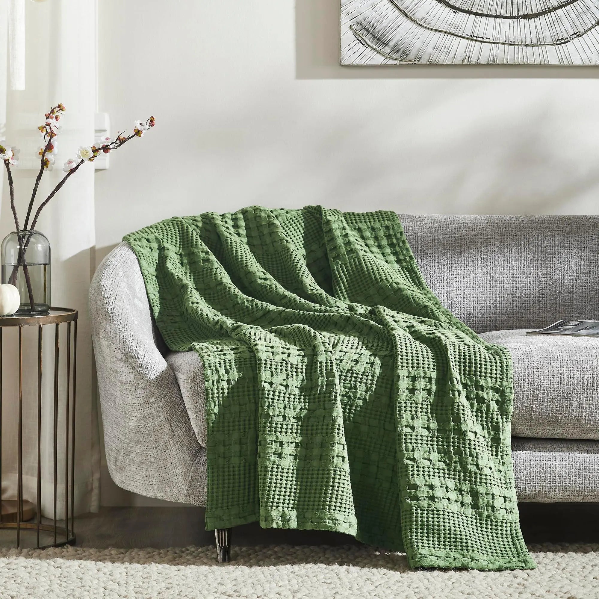 Green waffle knit throw blanket draped on cozy gray sofa, perfect for farmhouse or cottage living room decor
