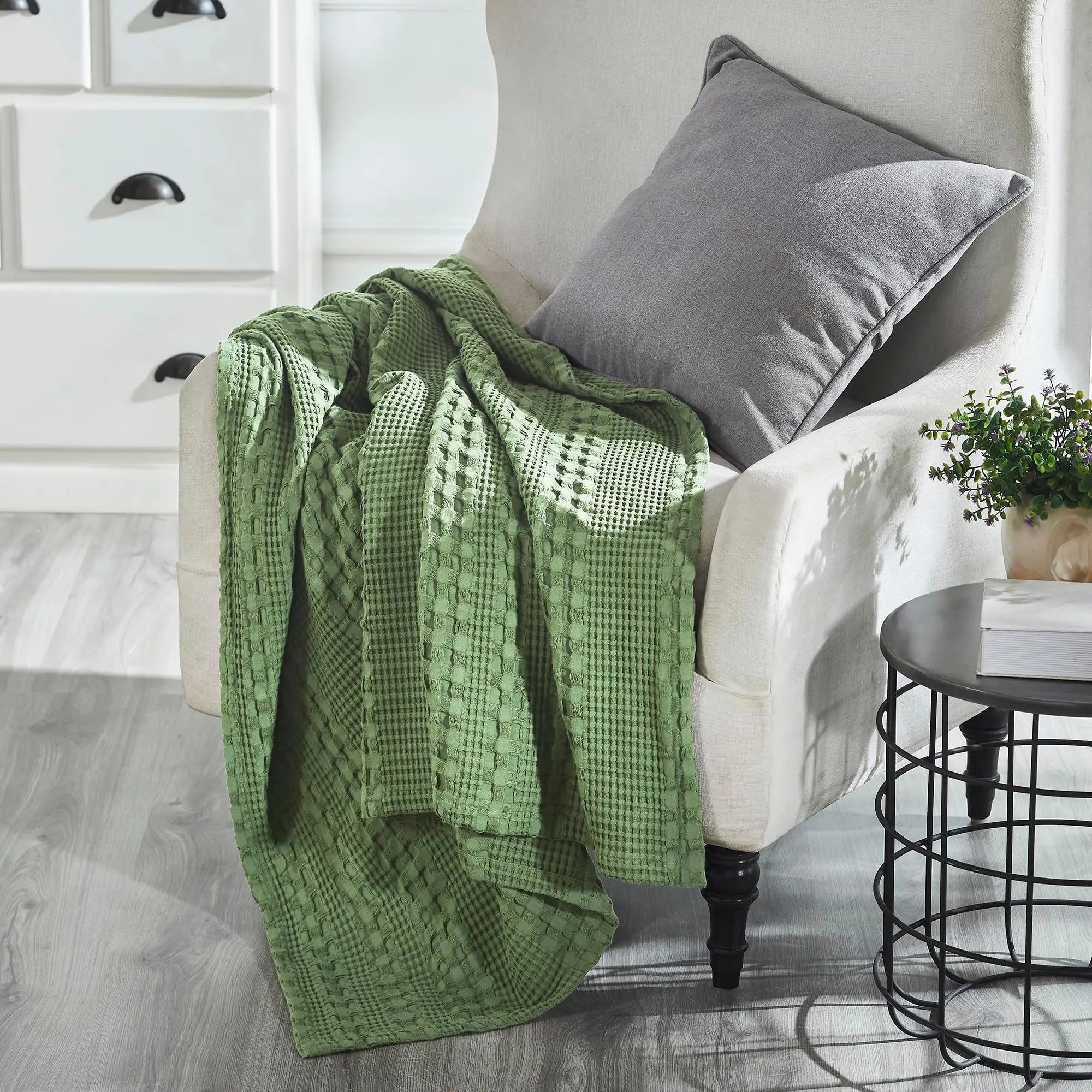 Green waffle knit throw blanket on cozy armchair with gray pillow, farmhouse decor