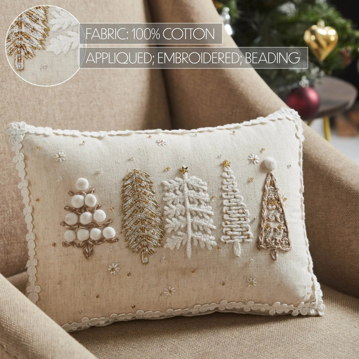 Decorative pillow with embroidered trees on a beige couch, Christmas tree in the background.