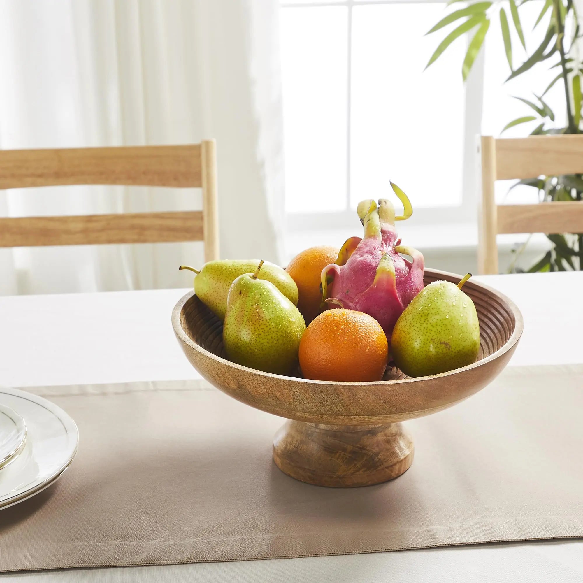 Wooden bowl with fruits on a table in a bright room