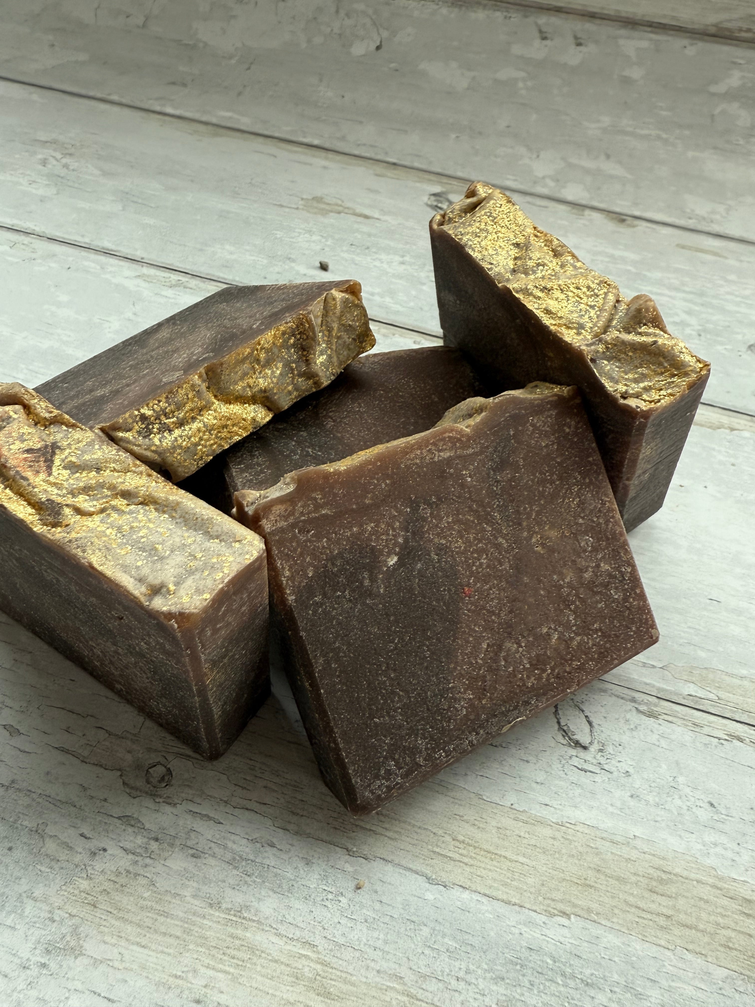Five pieces of brown soap on a light wooden surface